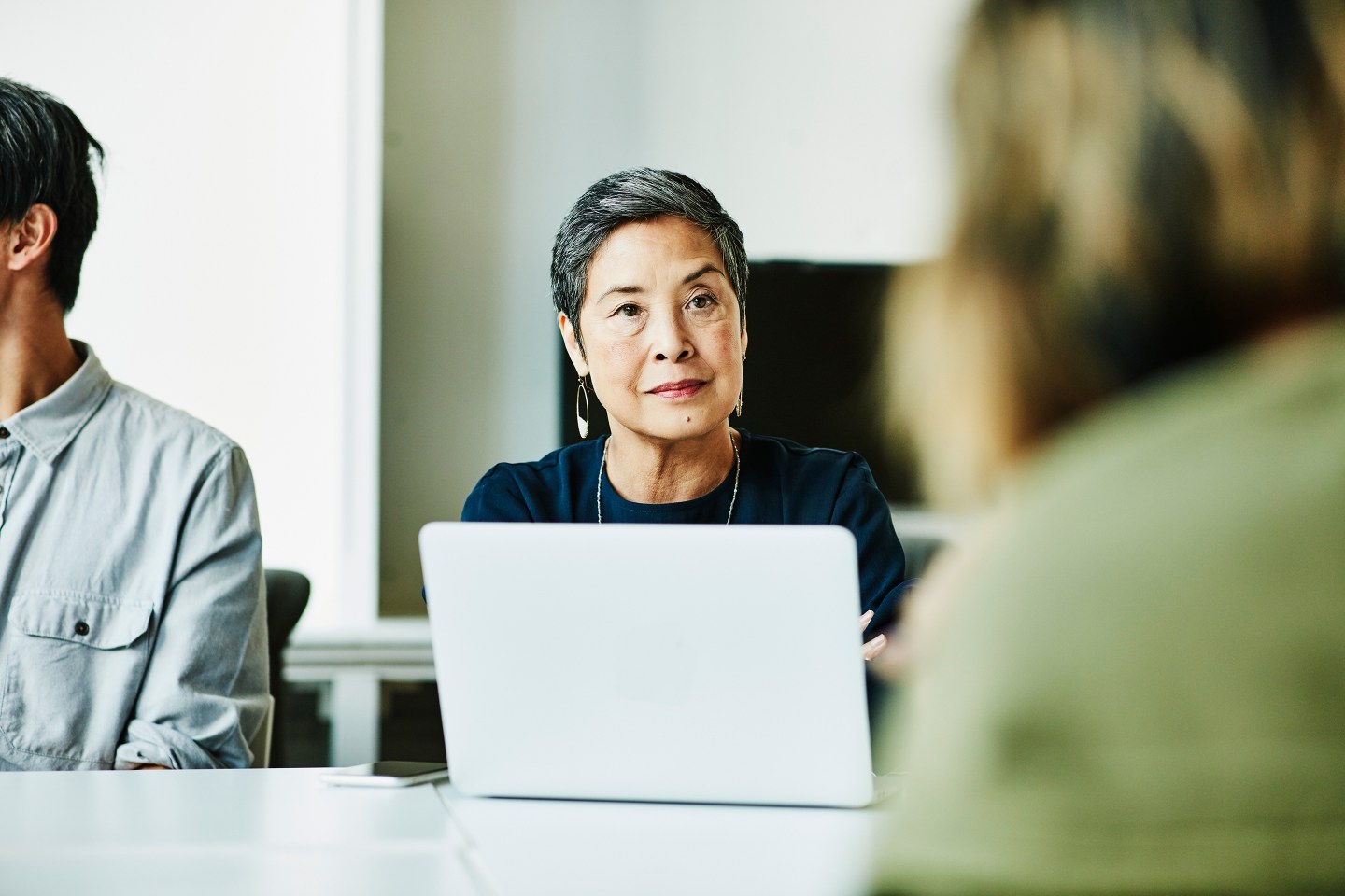 Senior businesswoman listening in office conference room.