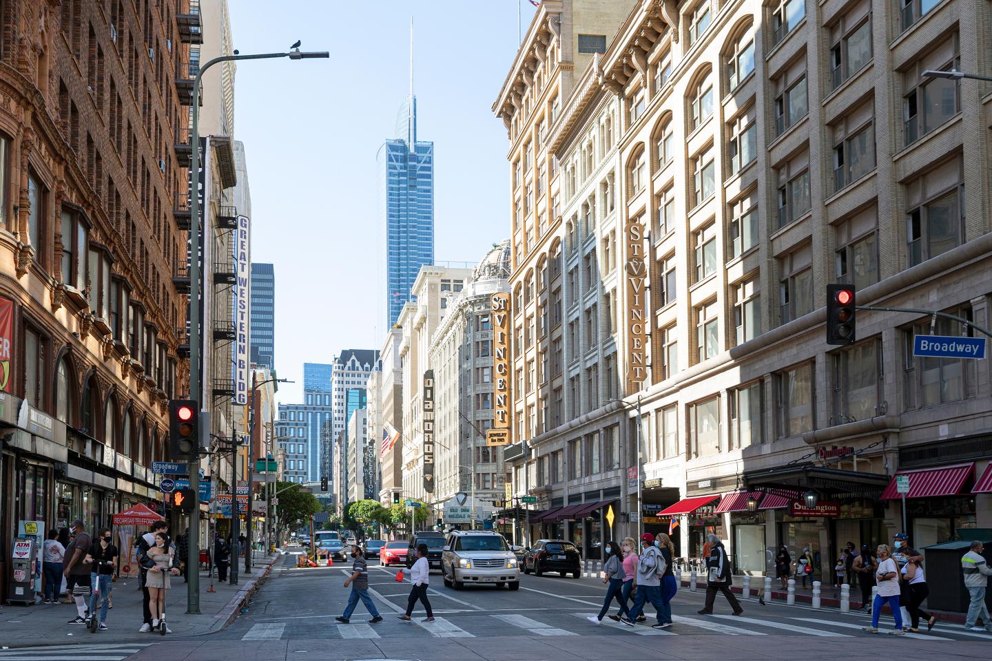 eople wearing protective face masks due to COVID-19, crossing the street in downtown LA.