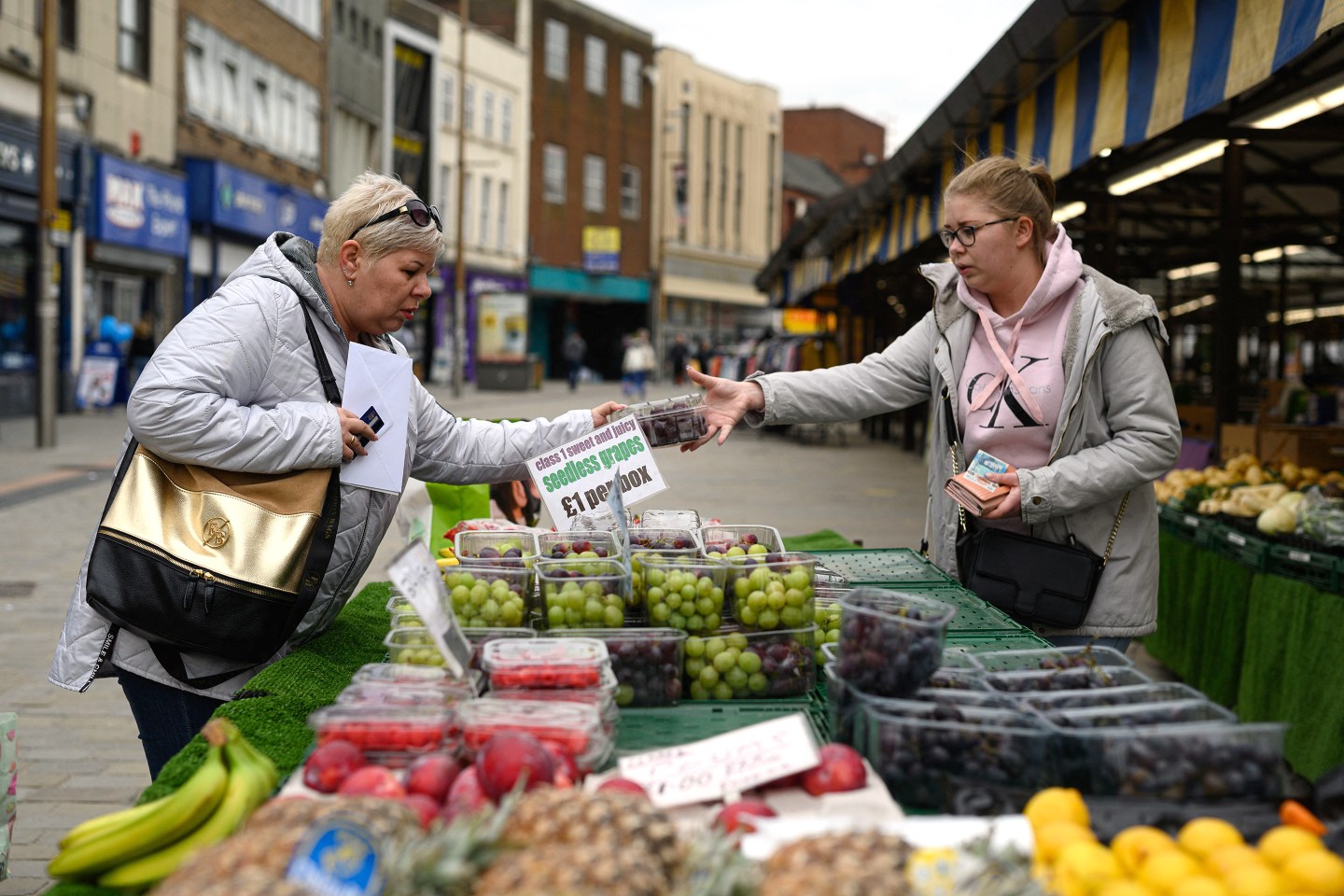 Shoppers make purchases at a market stall in Dudley town centre in central England on April 29, 2022.