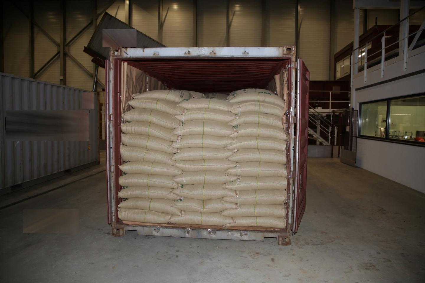An open shipping container reveals piles of large bags containing an unidentified product.