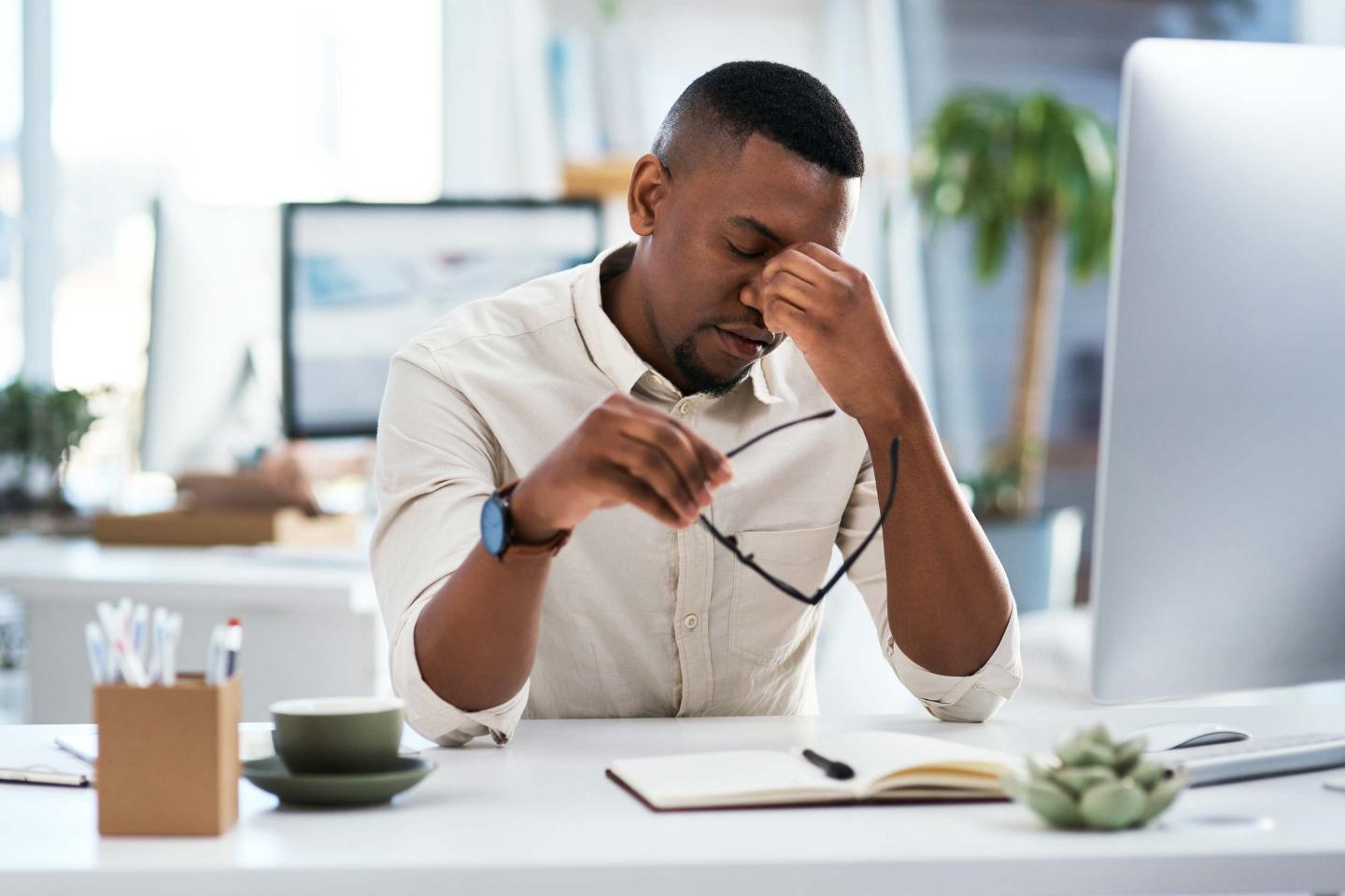 a man holding glasses and rubbing his eyes.