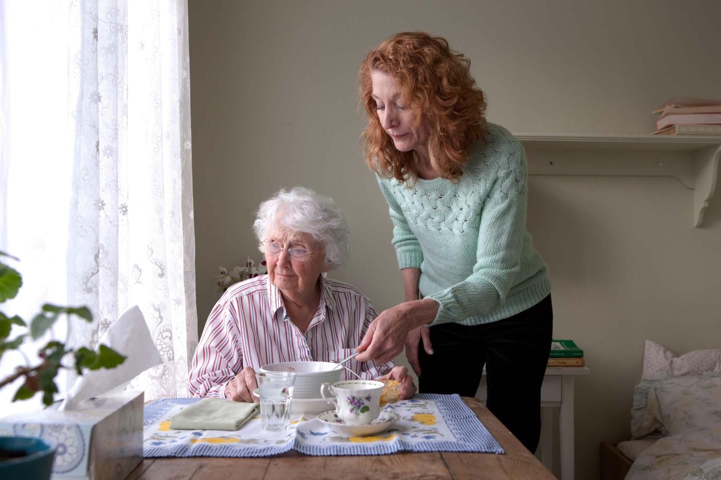 Woman feeding mother at table
