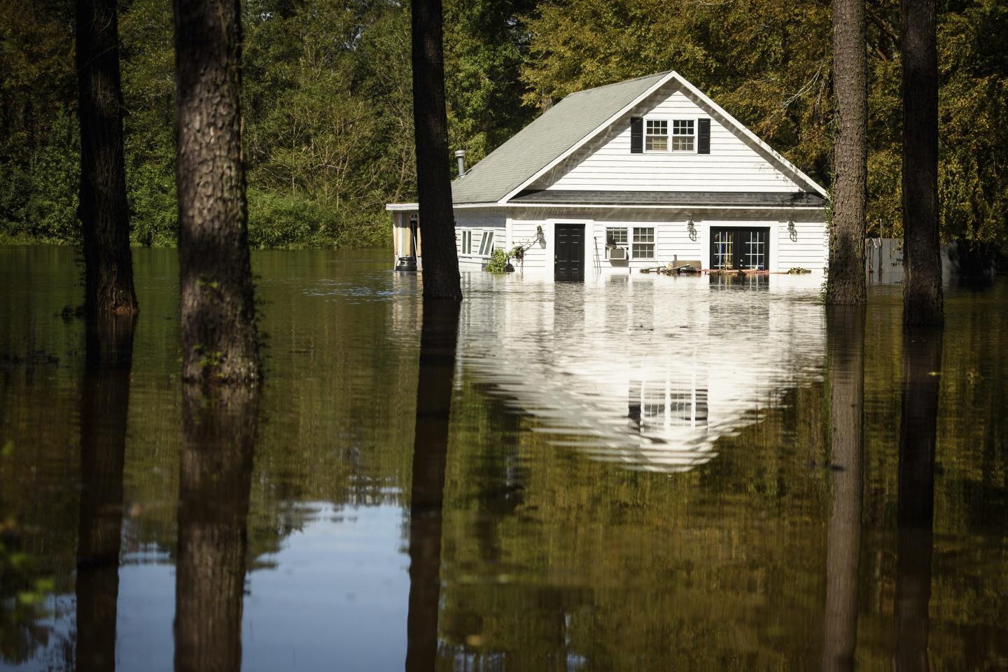 A home is surrounded by flooded waters from Hurricane Florence off of U.S. 401 near Linden, N.C., on Tuesday, Sept. 18, 2018. Hot real estate markets have made some homeowners wary of participating in voluntary flood buyout programs, impacting efforts to move people away from flooding from rising seas, intensifying hurricanes and more frequent storms.  Flood buyout programs typically purchase flood-prone homes, raze them and turn the property into green space.