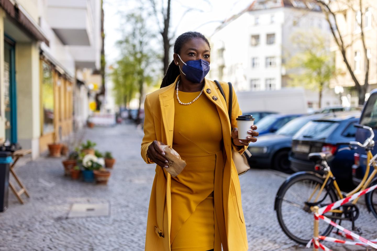 Black woman wearing a face mask commuting to work with breakfast.