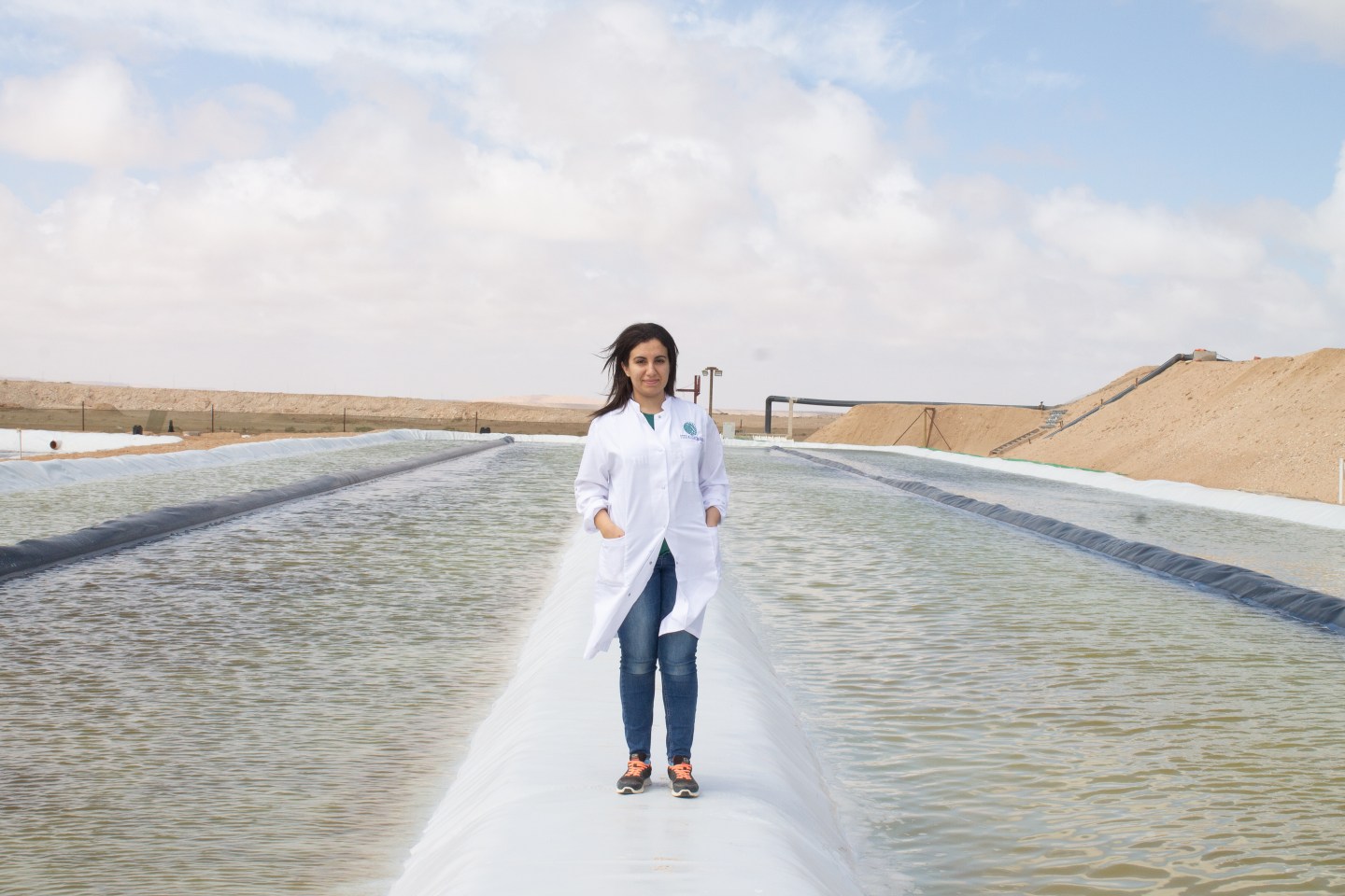 Besma Bouchrit, a research scientist for Brilliant Planet, stand in the middle of an algae farm.