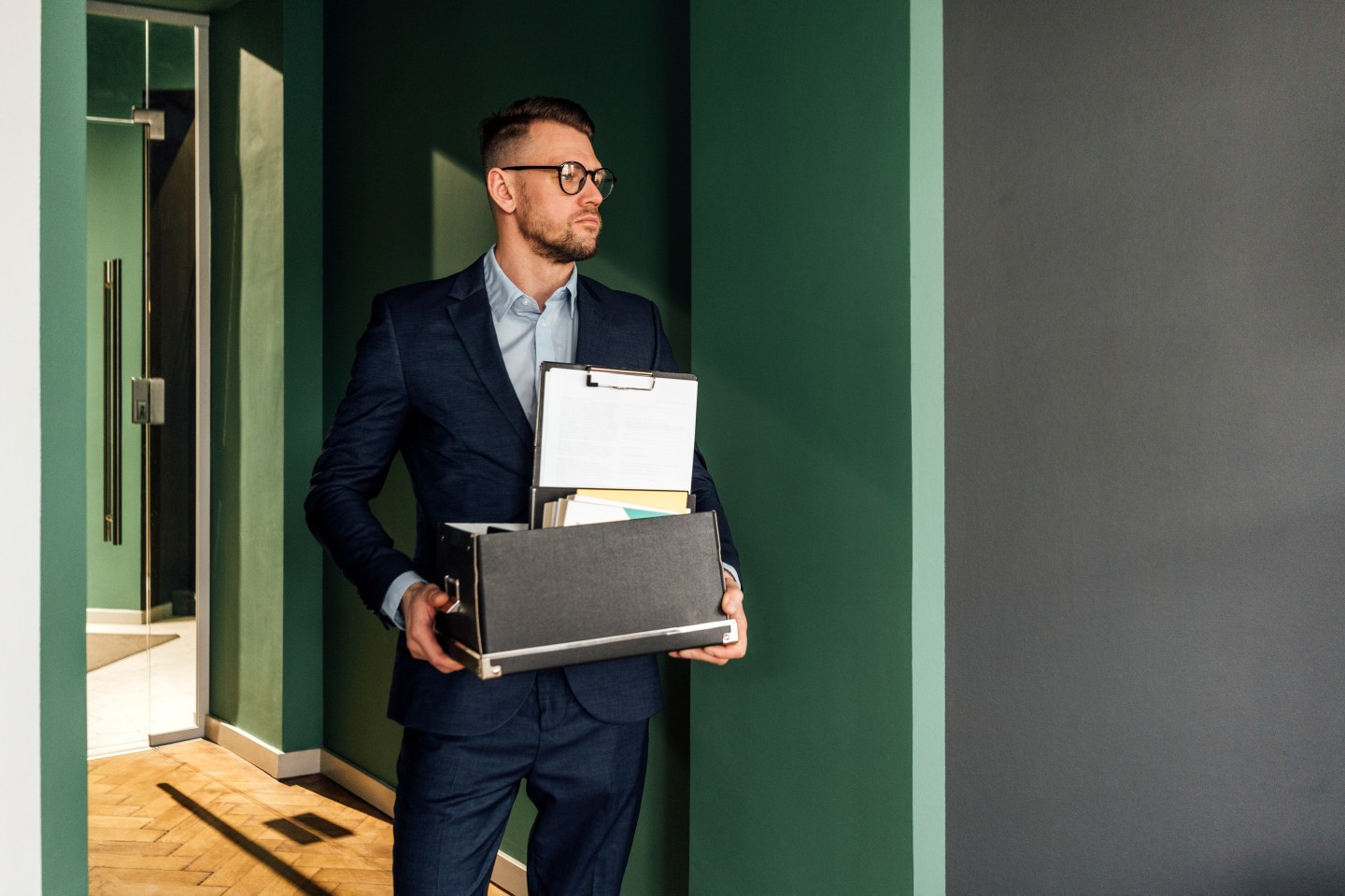 C Suite businessman leaving office with box of belongings.