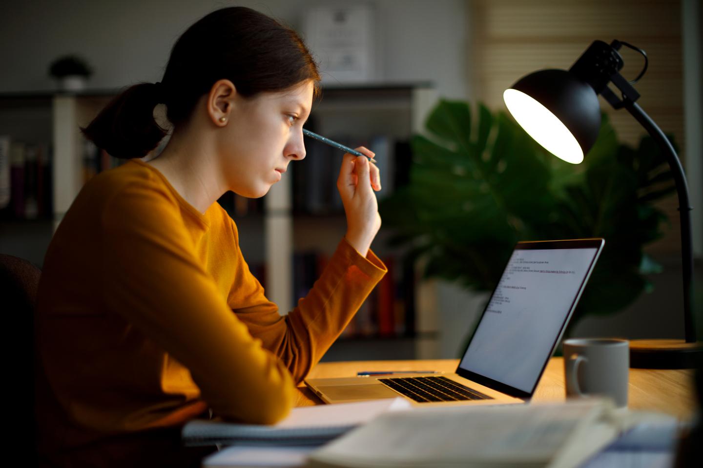 Exhausted teenage girl working late at home on her computer.