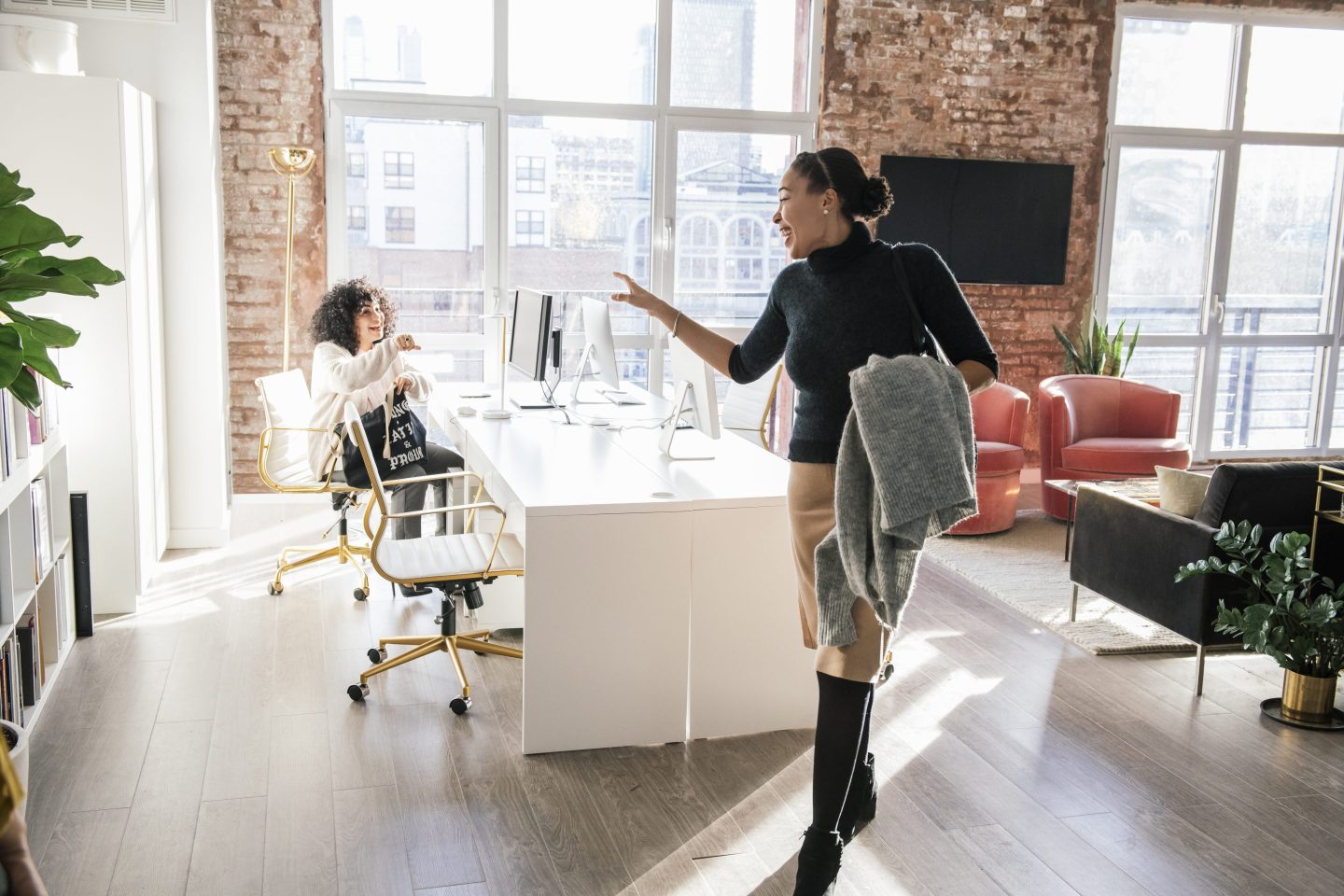 A woman cheerfully waves goodbye to a colleague as she leaves the office