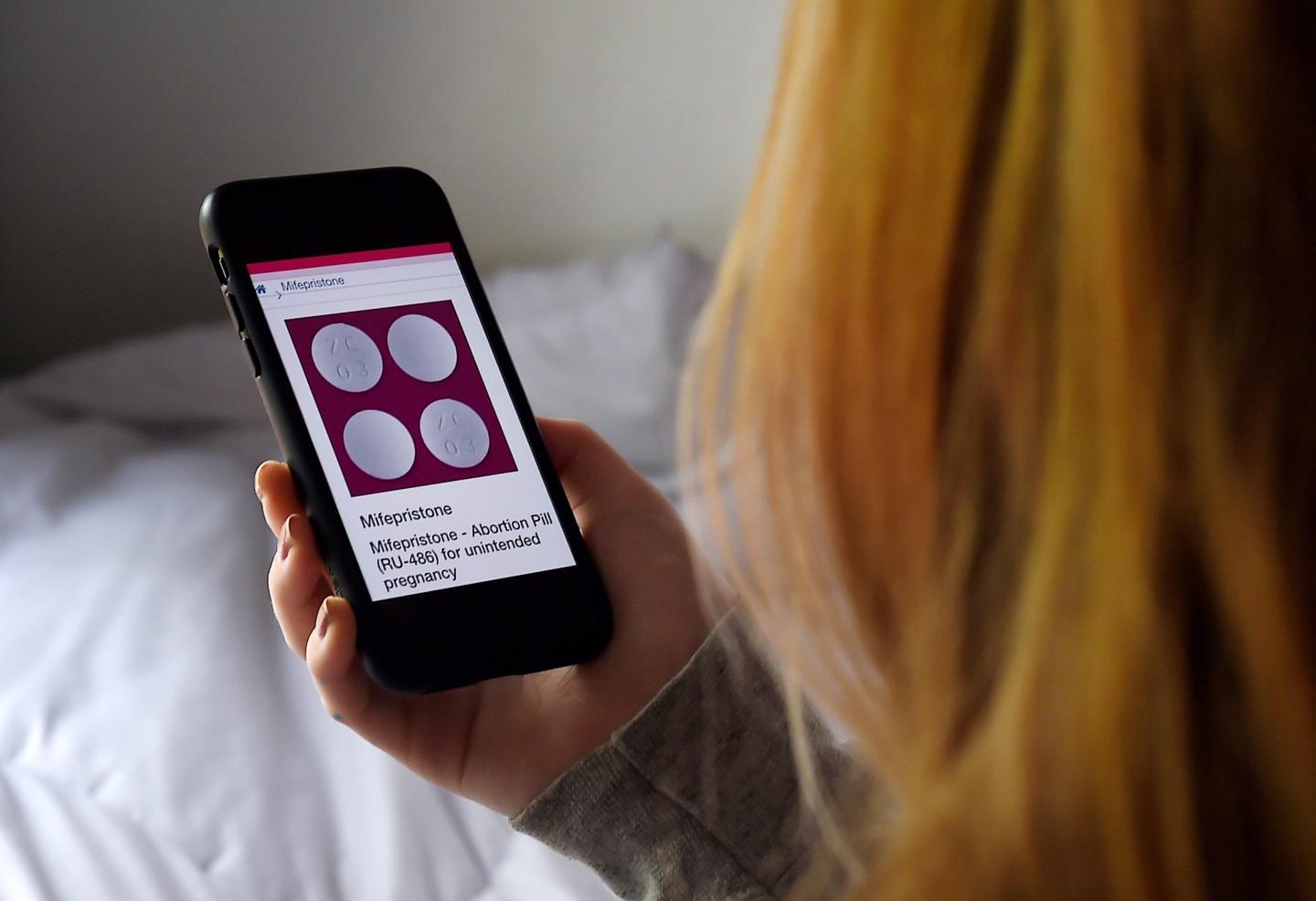 A person looking at a picture of an abortion pill on their phone