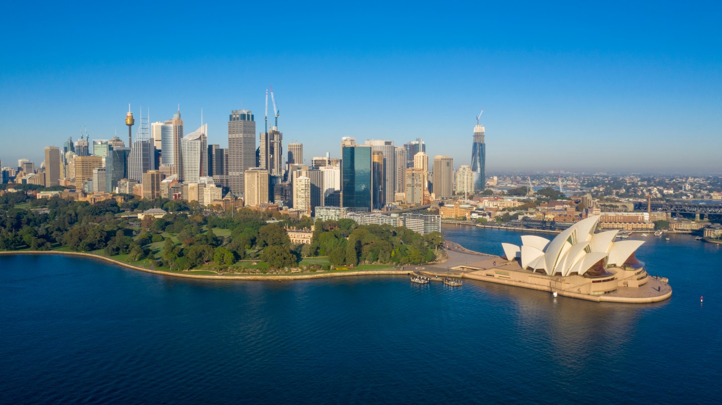 The Sydney Opera House and general harbour and cityscape during sunrise.