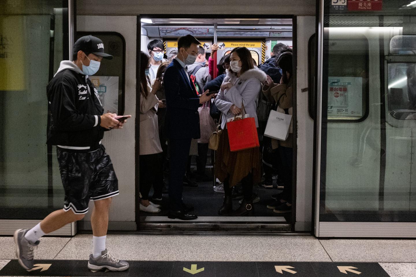 ommuters wearing face masks as a precaution against the spread of Covid-19 standing inside the MTR subway train in Hong Kong.