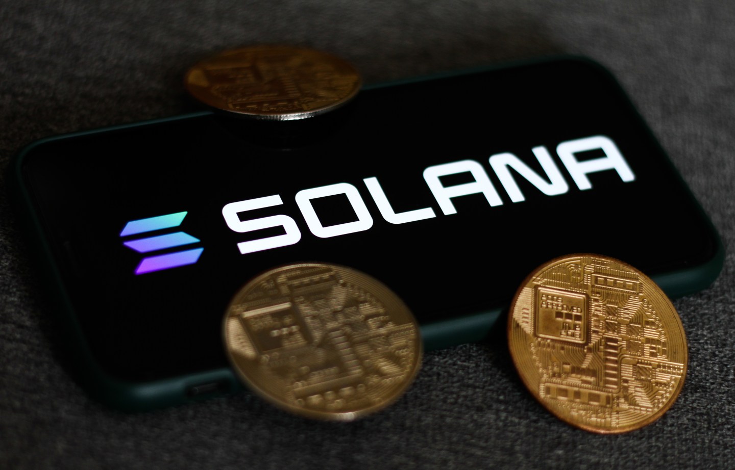 A photo illustration showing the Solana brand name and some coins