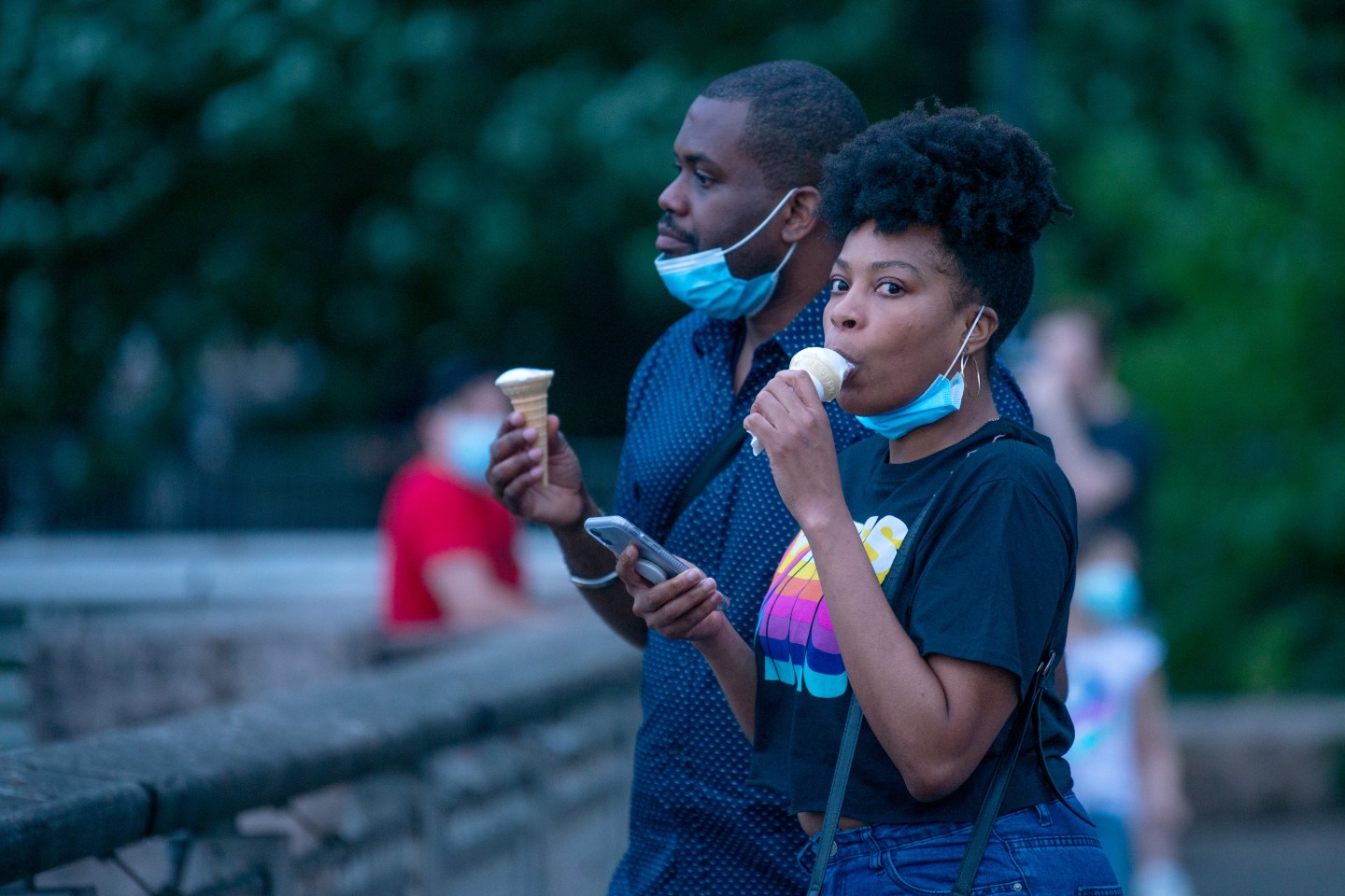A woman pulls down her mask to eat ice cream at Gantry Plaza State Park in Long Island City, N.Y.
