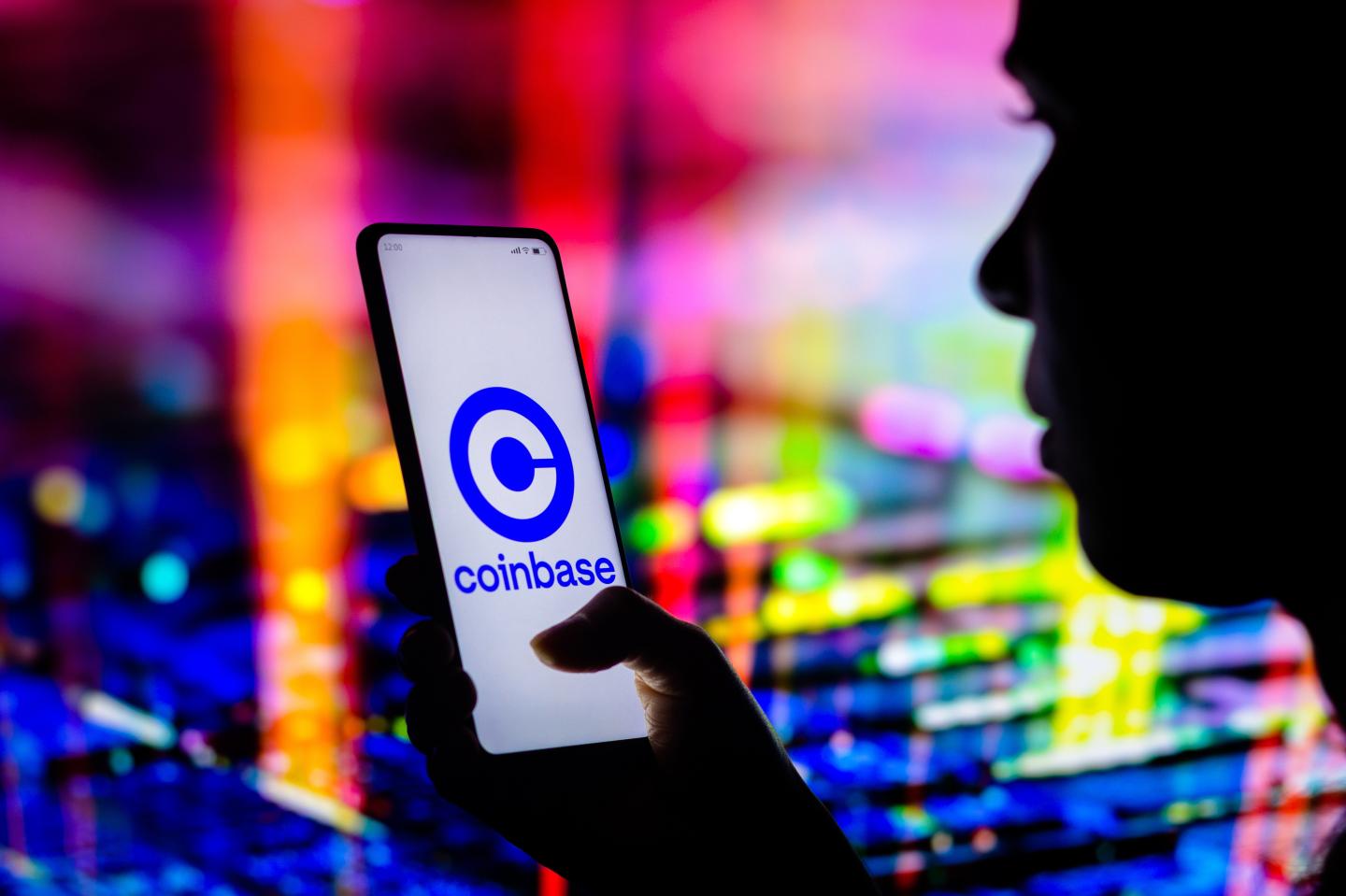 A woman holding a phone with the Coinbase logo.