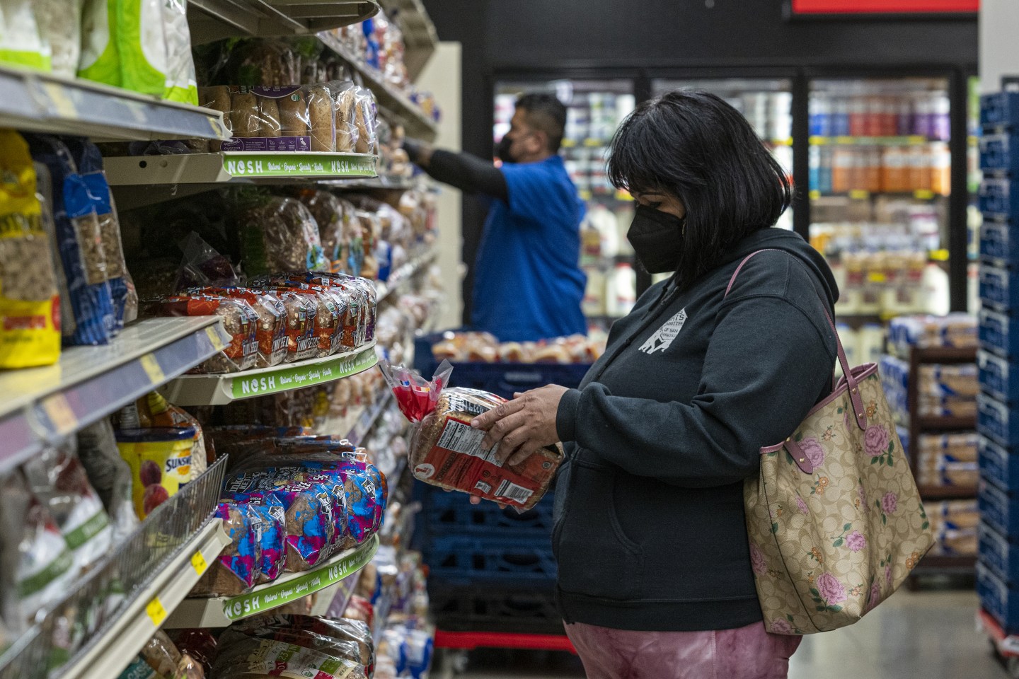 A shopper checks a loaf of bread inside a grocery store