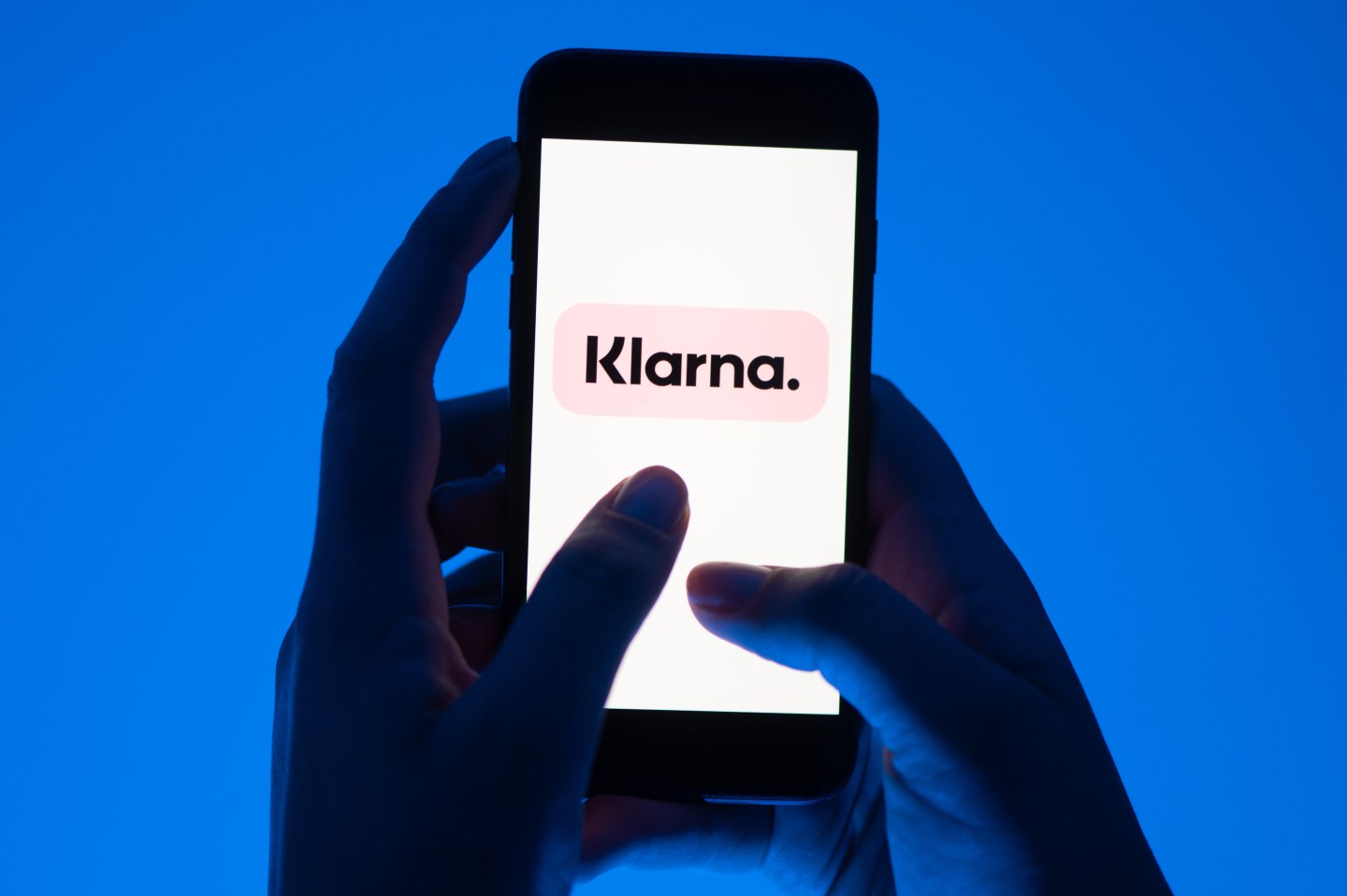 A woman holds a smartphone with the logo of the Klarna payment service.