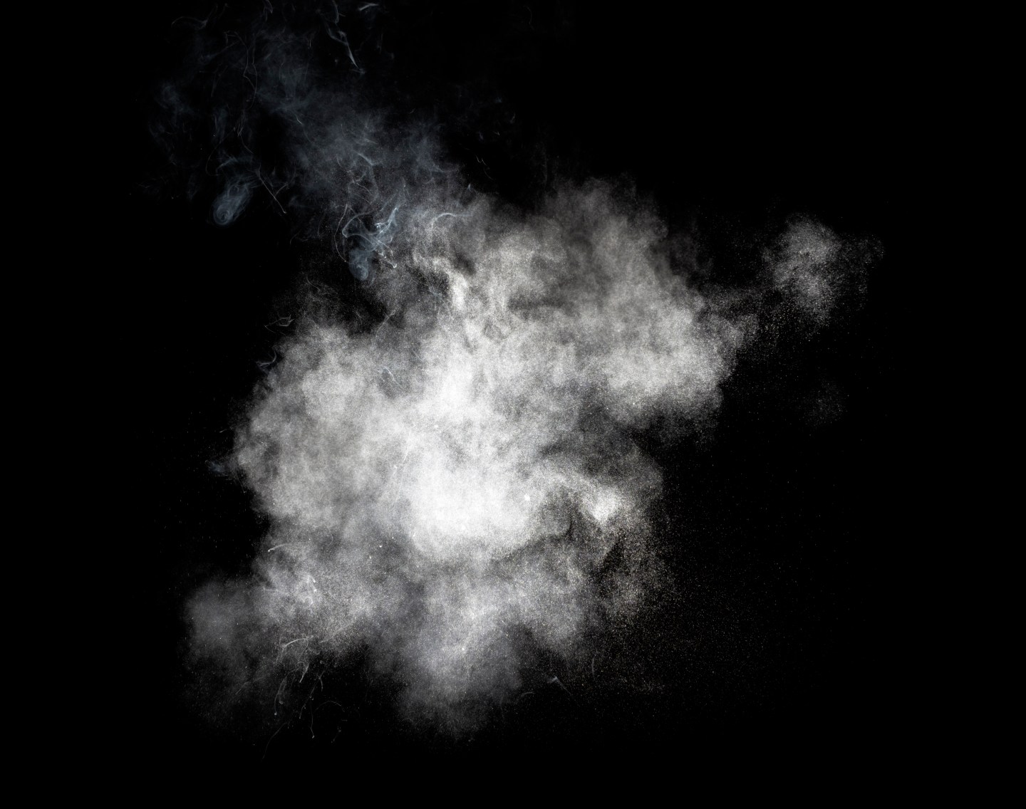Explosion of a cloud of particles of smoke of white color on a black background.