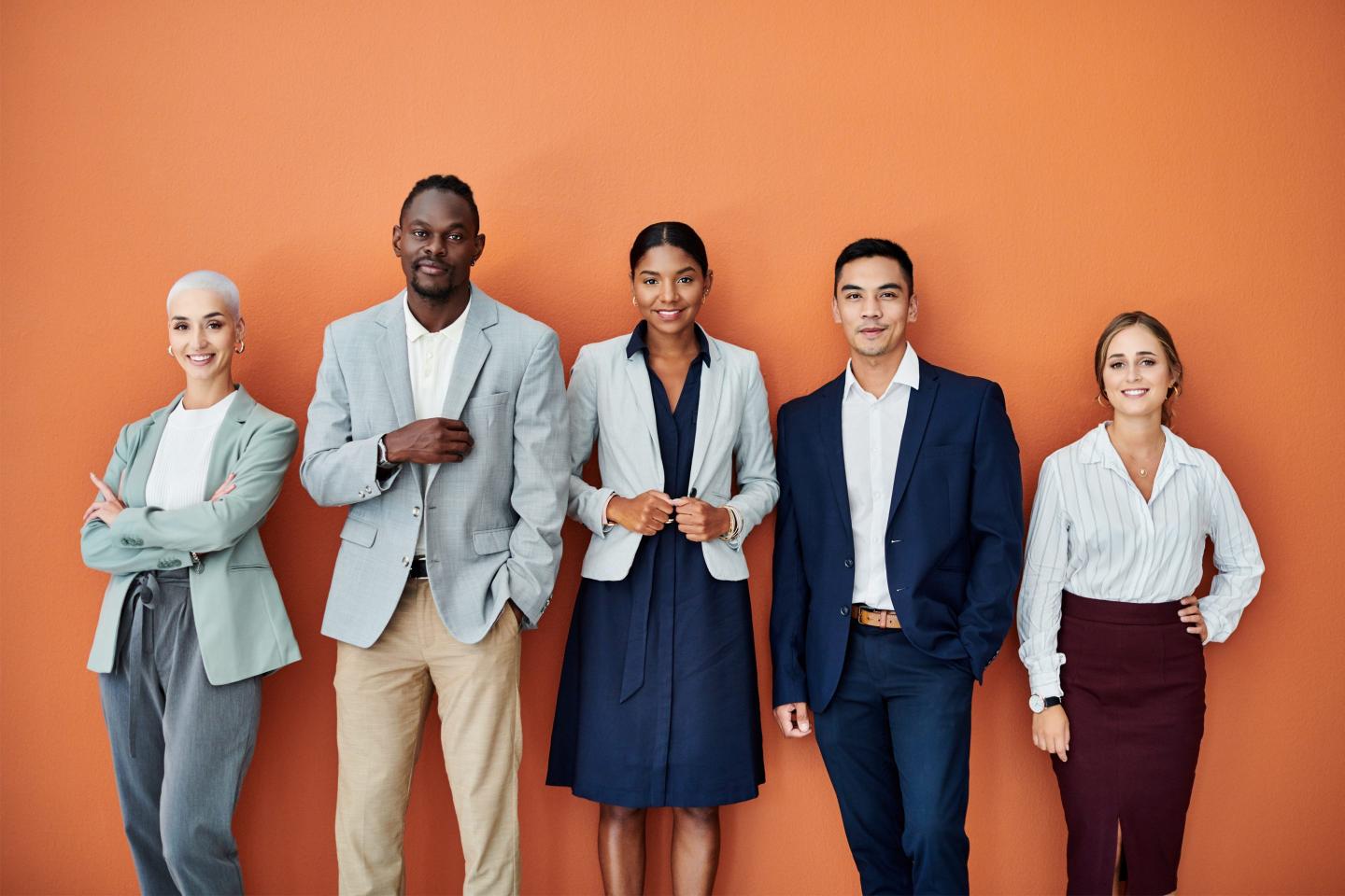Portrait of a group of businesspeople standing together against an orange background