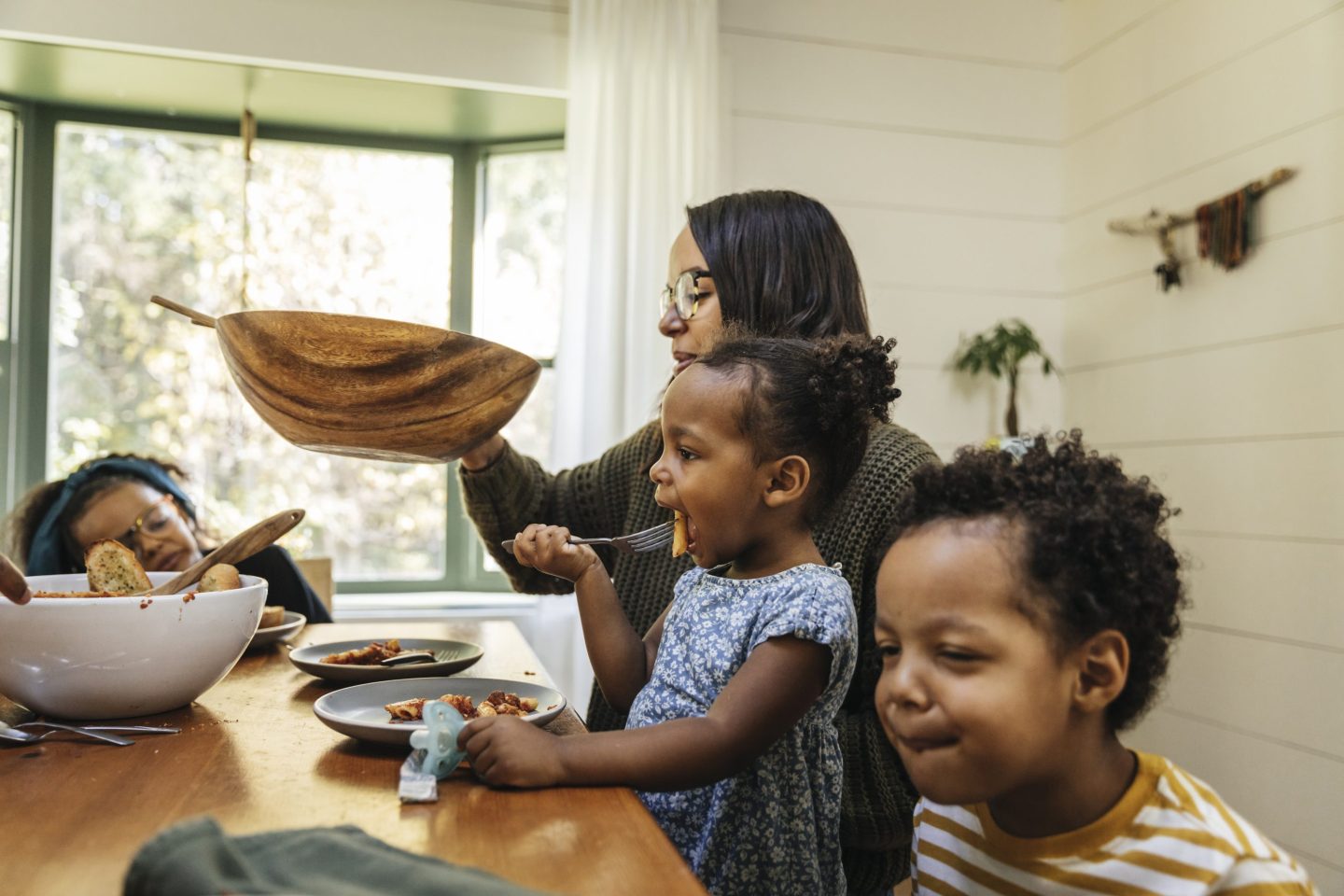 Mother passing salad bowl during family meal