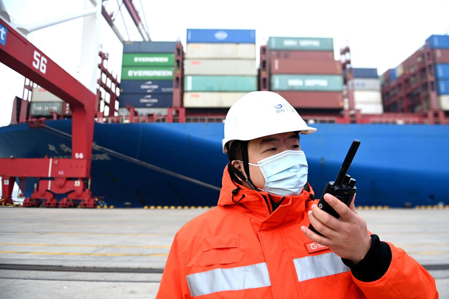 A dockworker directs container ship CSCL GLOBE to lift a container unit at Qingdao Port on December 23, 2021 in Qingdao, Shandong Province of China.