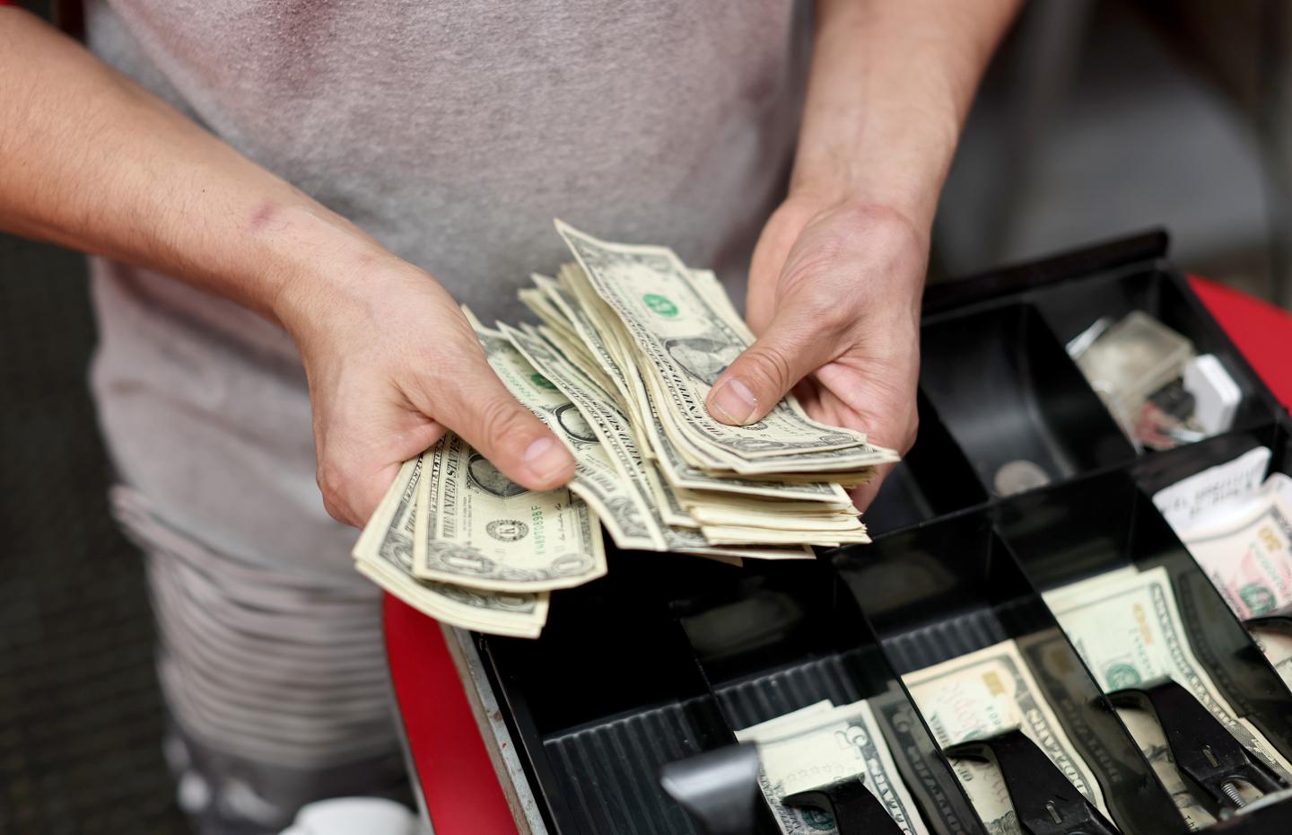 Cash register with clerk holding money.