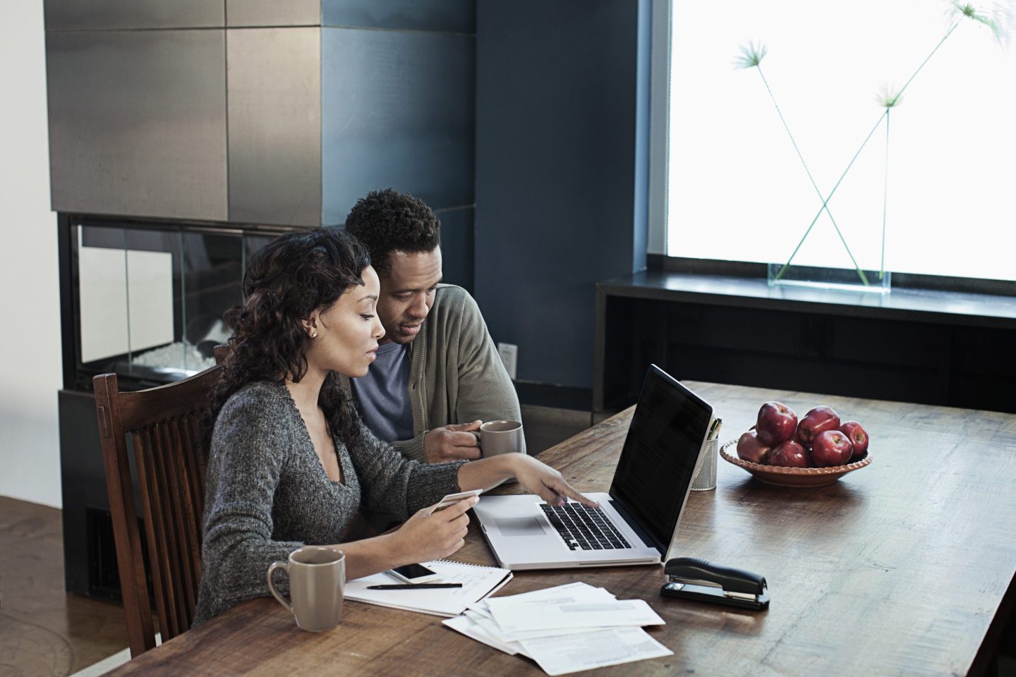 woman using laptop while husband drinks coffee