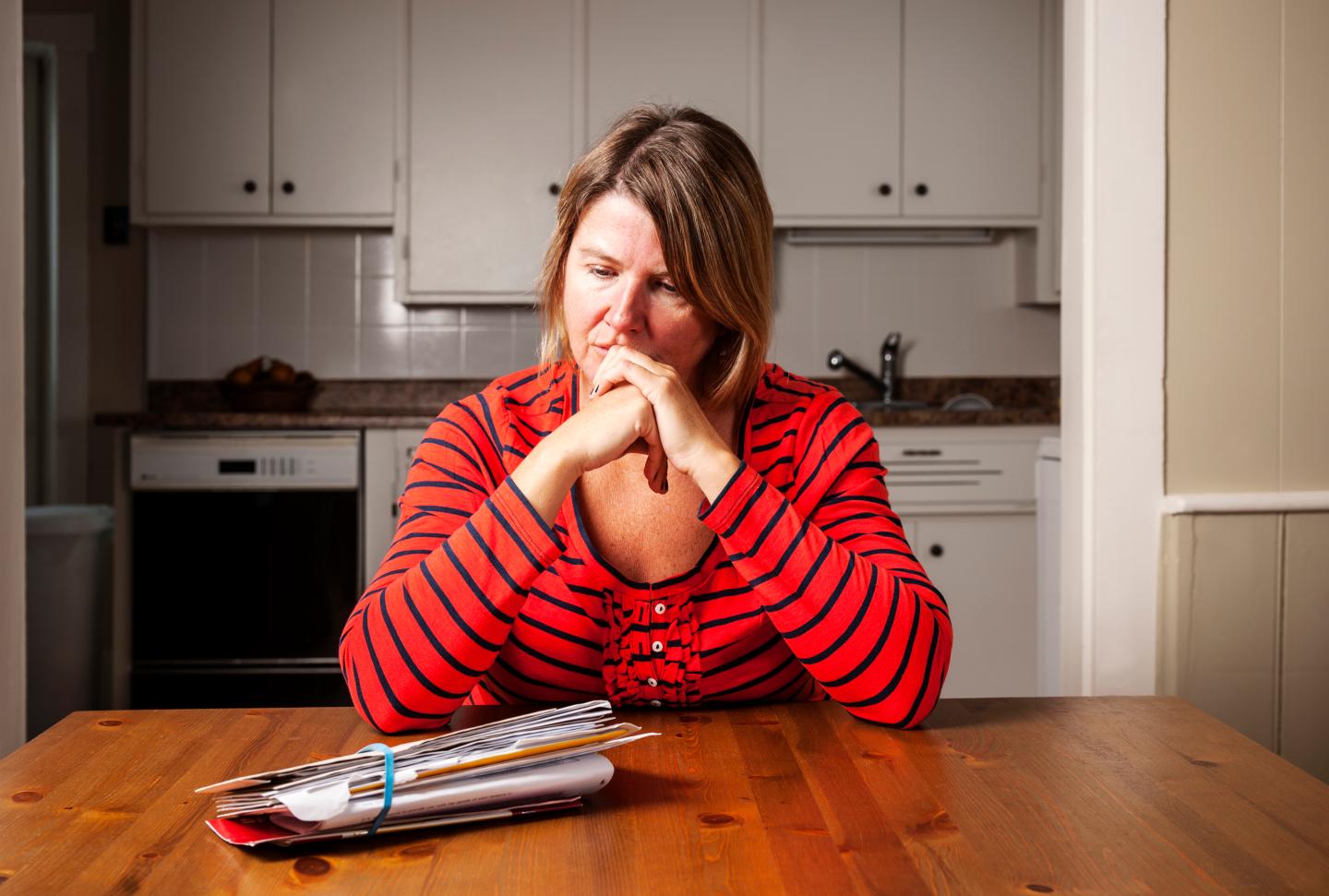Woman at kitchen table looking at her bills