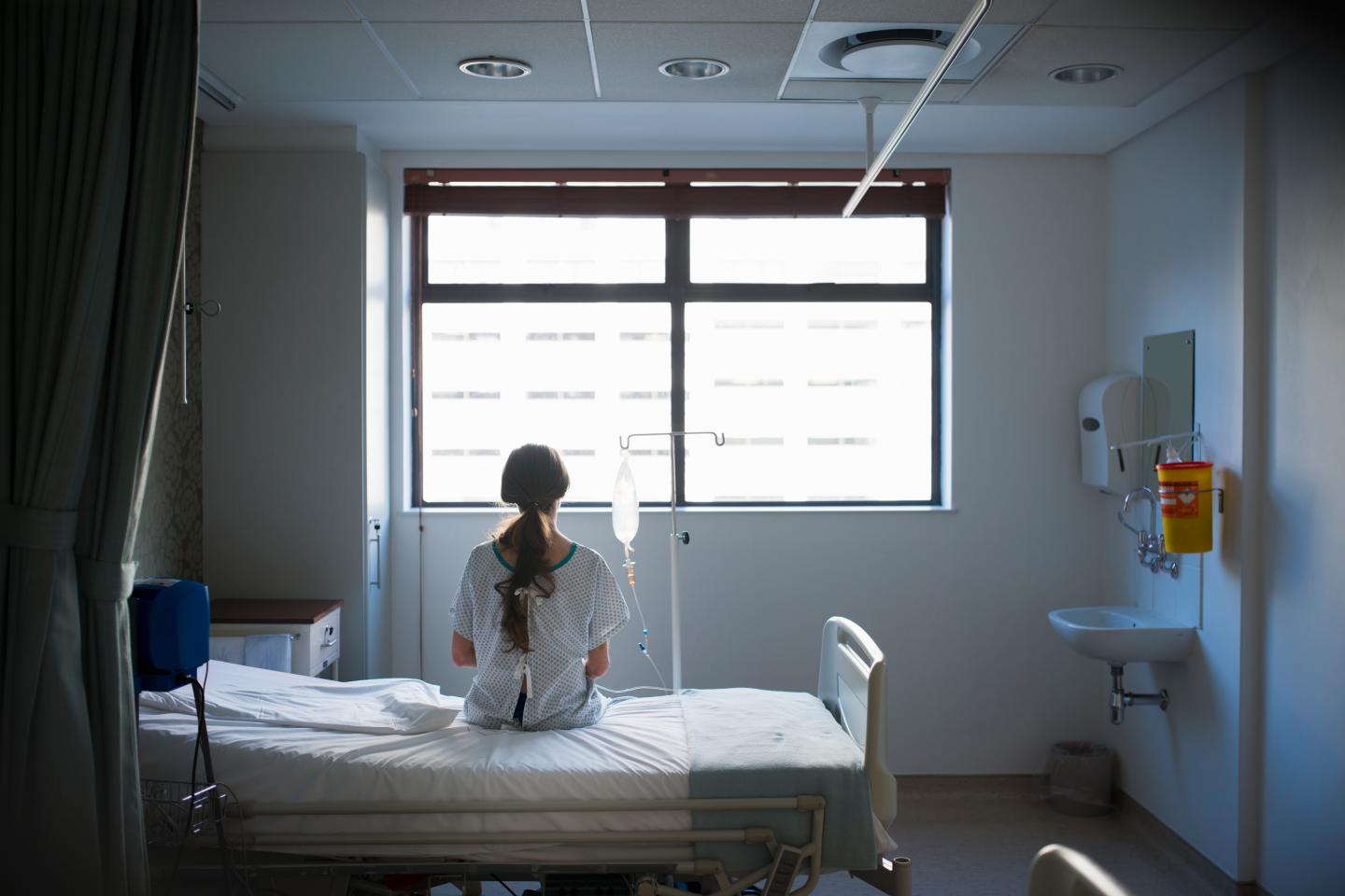 Patient sitting on hospital bed waiting.