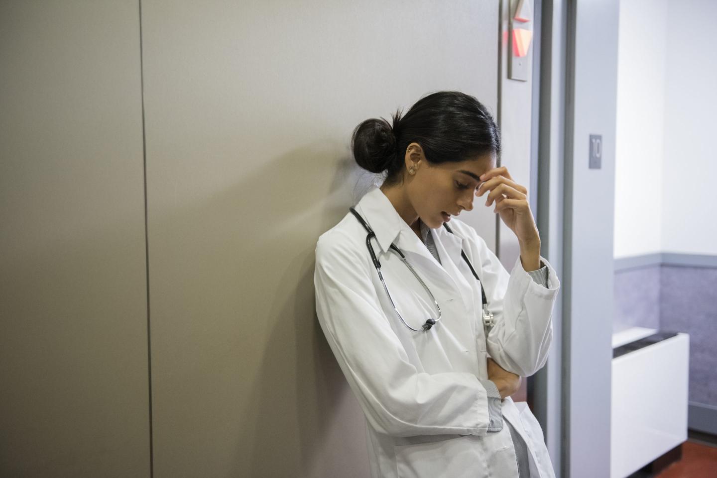 Stressed doctor leaning on wall.