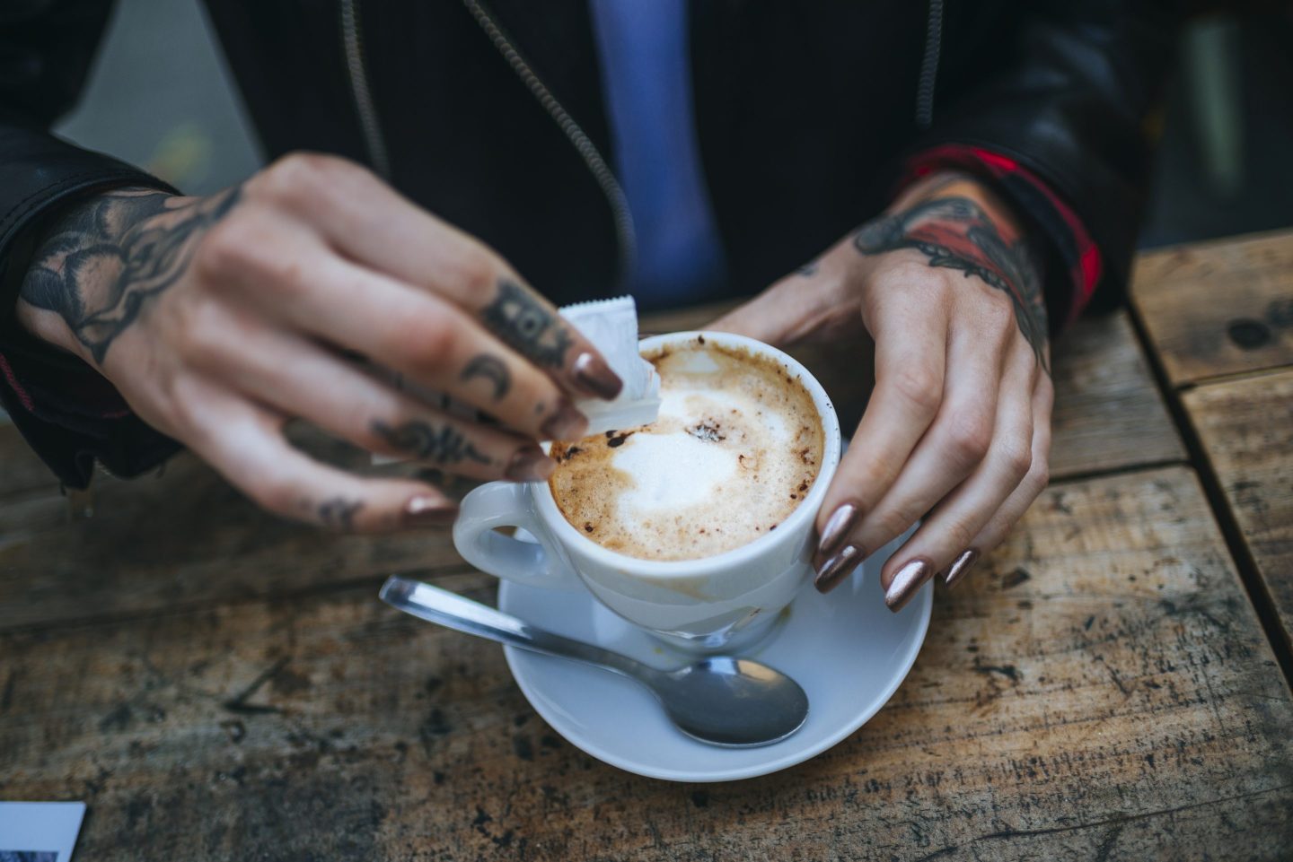 Spain, Catalonia, Barcelona, Close-up of woman hands pouring sugar into a coffee.