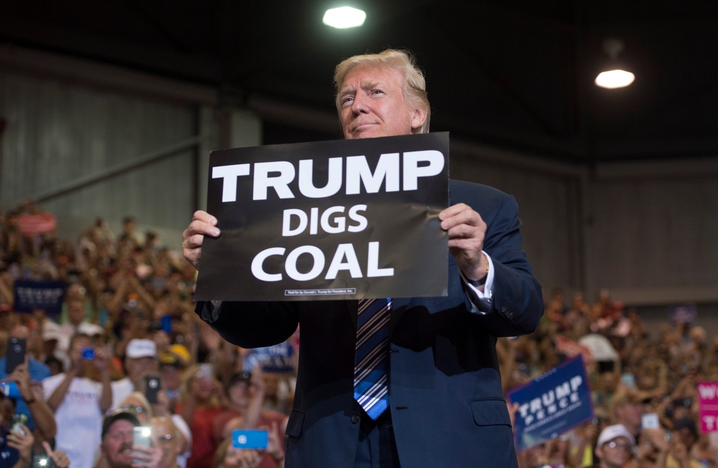 President Donald Trump holds a sign readign 'Trump digs coal' at a rally in 2017