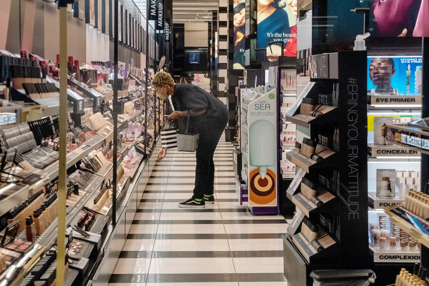 A worker arranges shelves at a Sephora store.