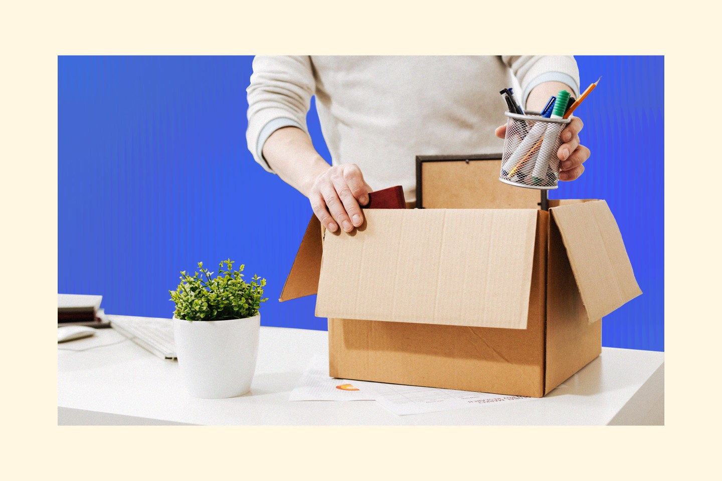Man packing box of office supplies from desk after getting laid off.