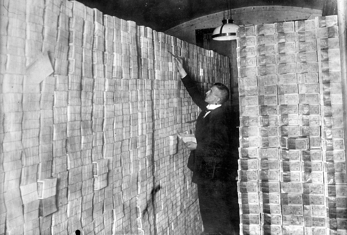 A man stands in front of stacks of banknotes in Germany in 1923.