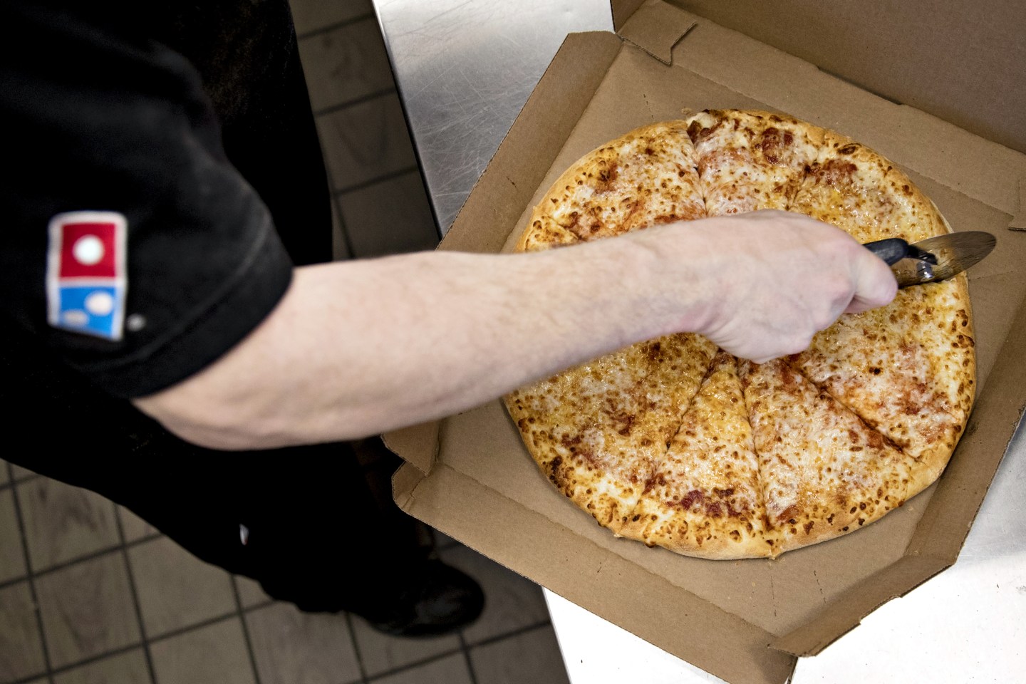 Domino's Pizza employee cuts a pizza pie before delivery.
