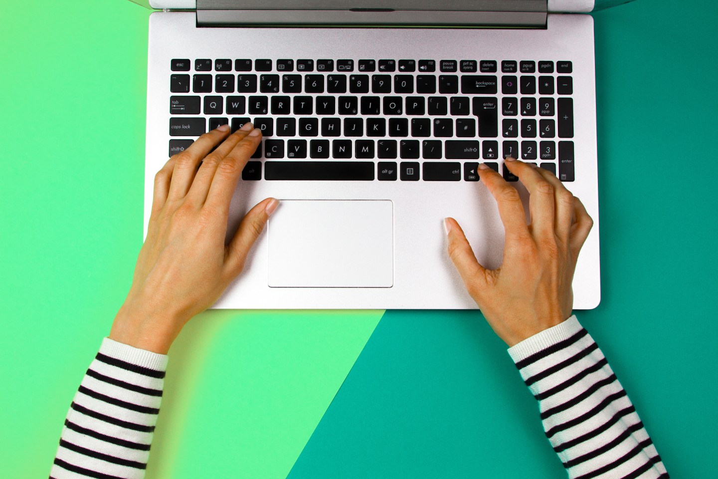 Hands Of Woman Using Laptop Over Colored Background