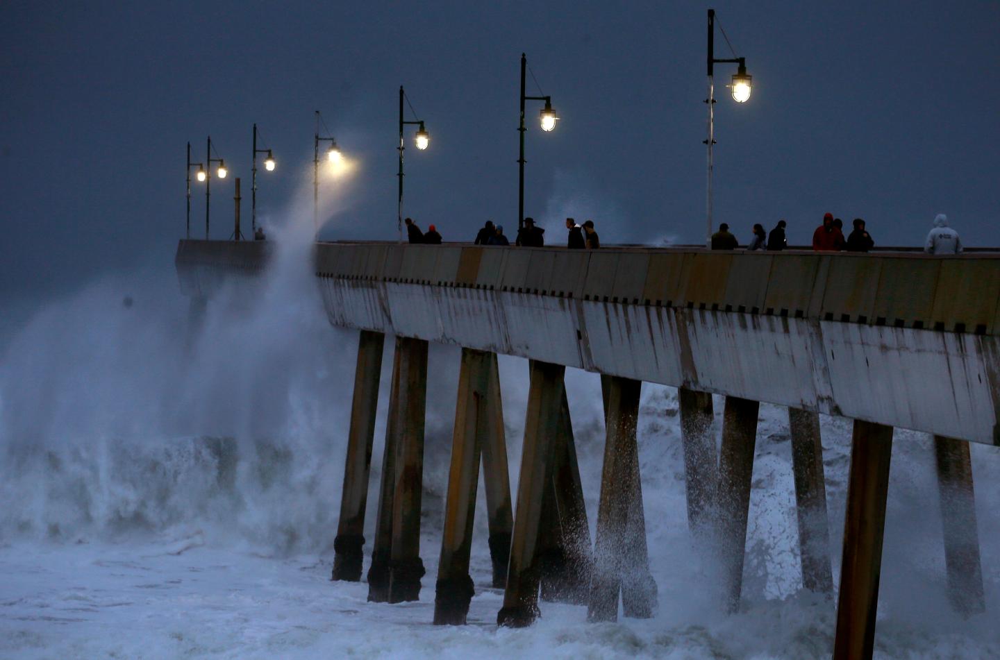 Big waves batter an ocean pier under dark skies