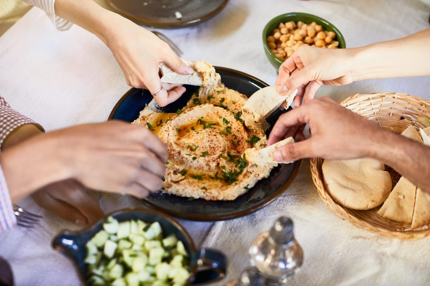 People dip into a bowl of hummus