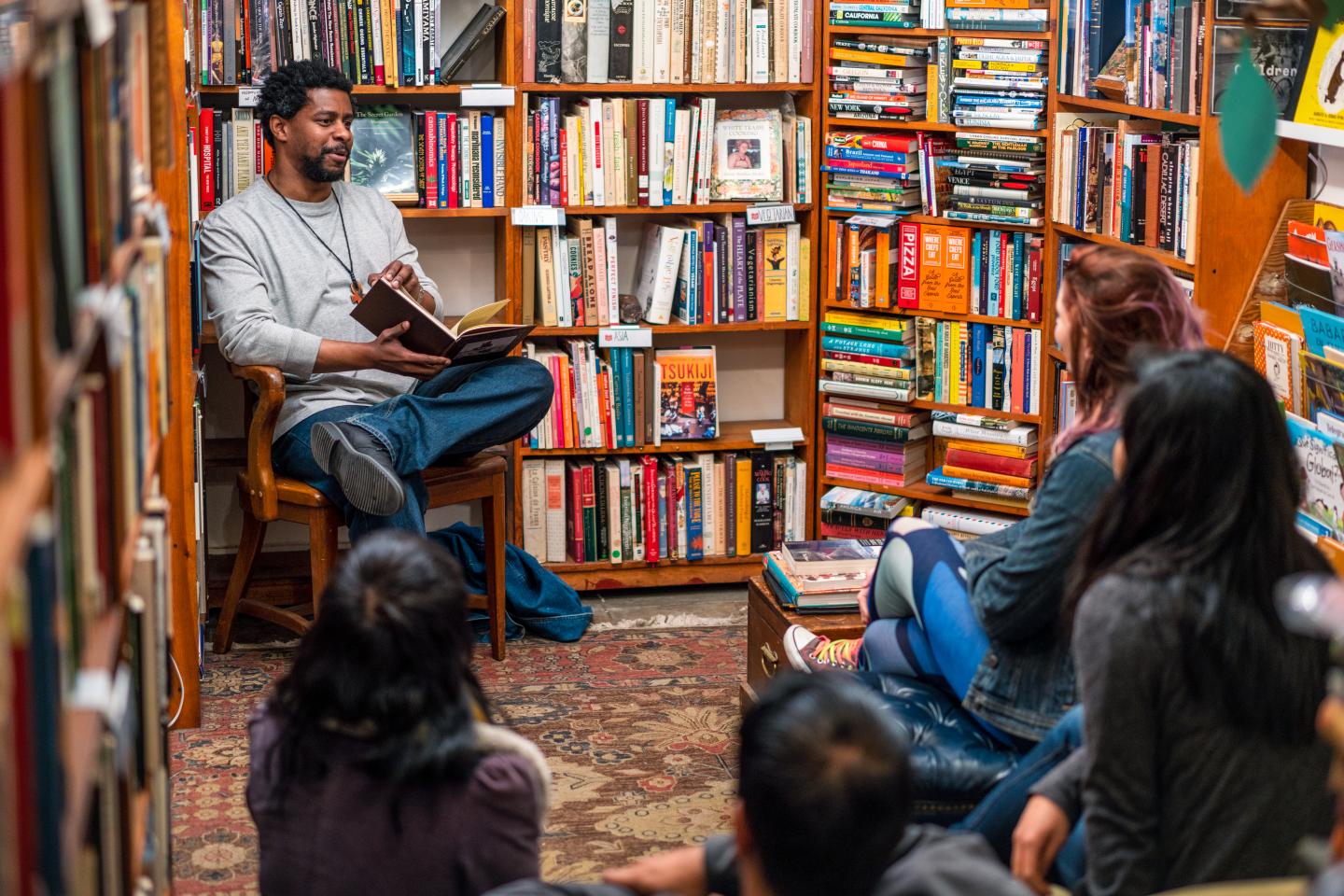 A man reads to a group of people in a bookstore