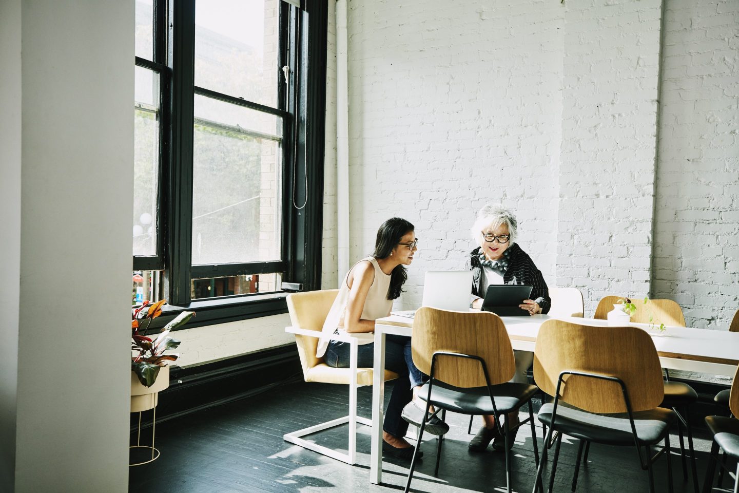 Senior businesswoman presenting project on digital tablet to colleague in conference room