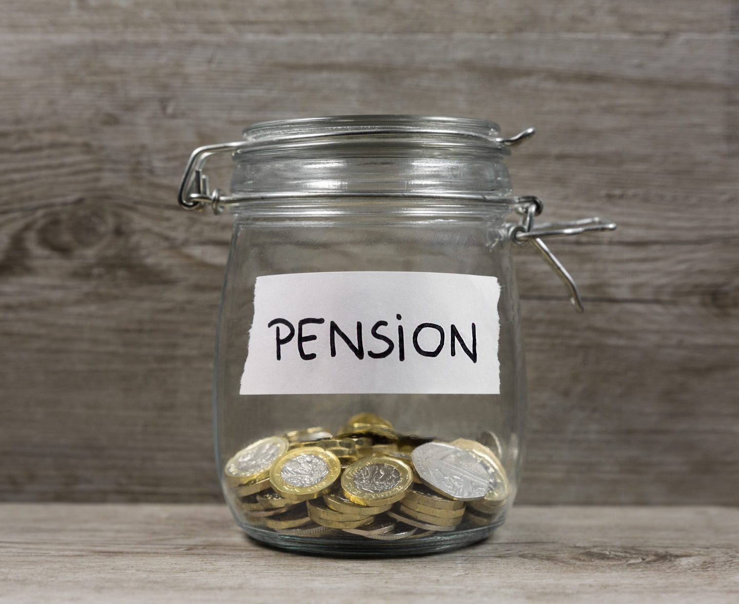 A jar labeled "Pension" is less than half way full with coins.