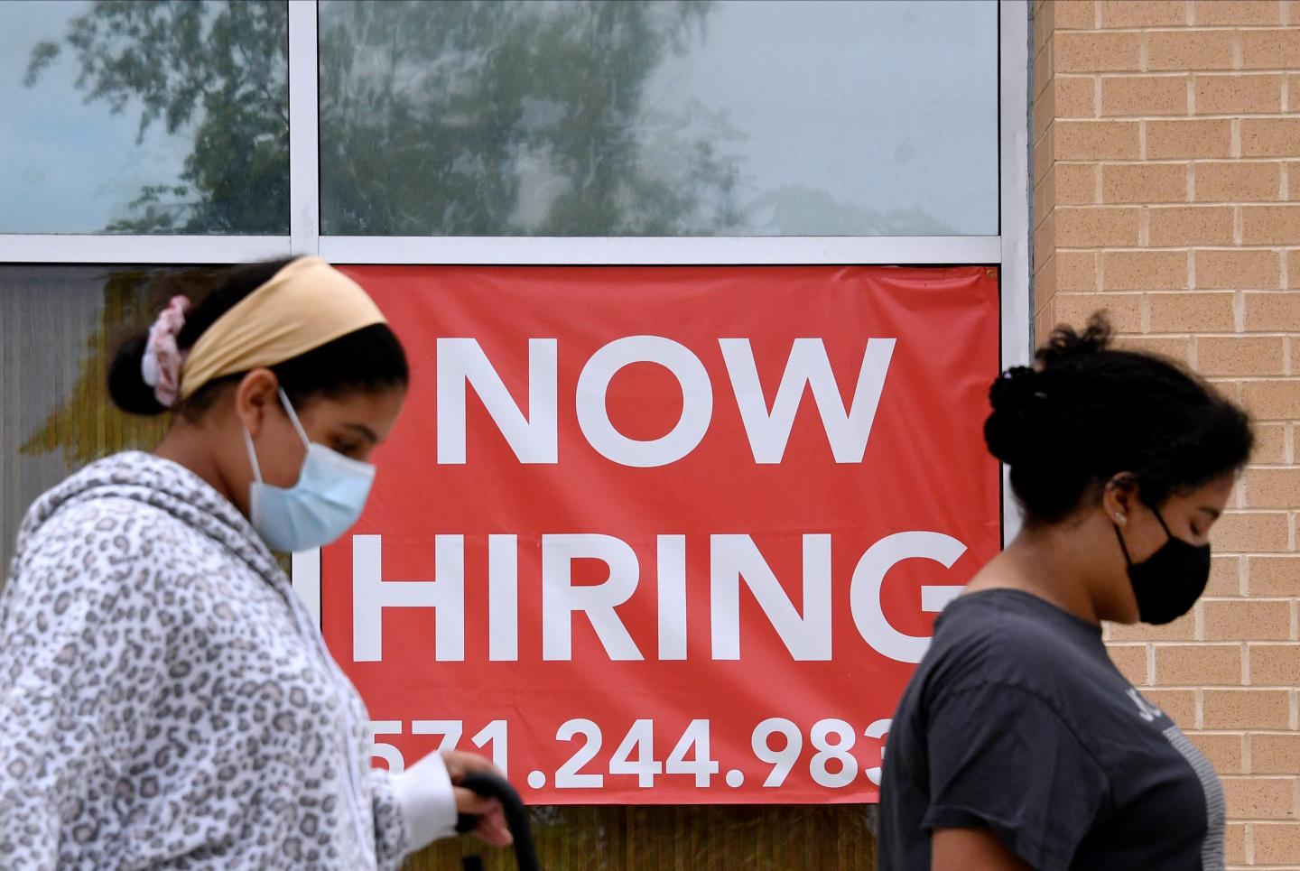 Women walking past a help wanted sign