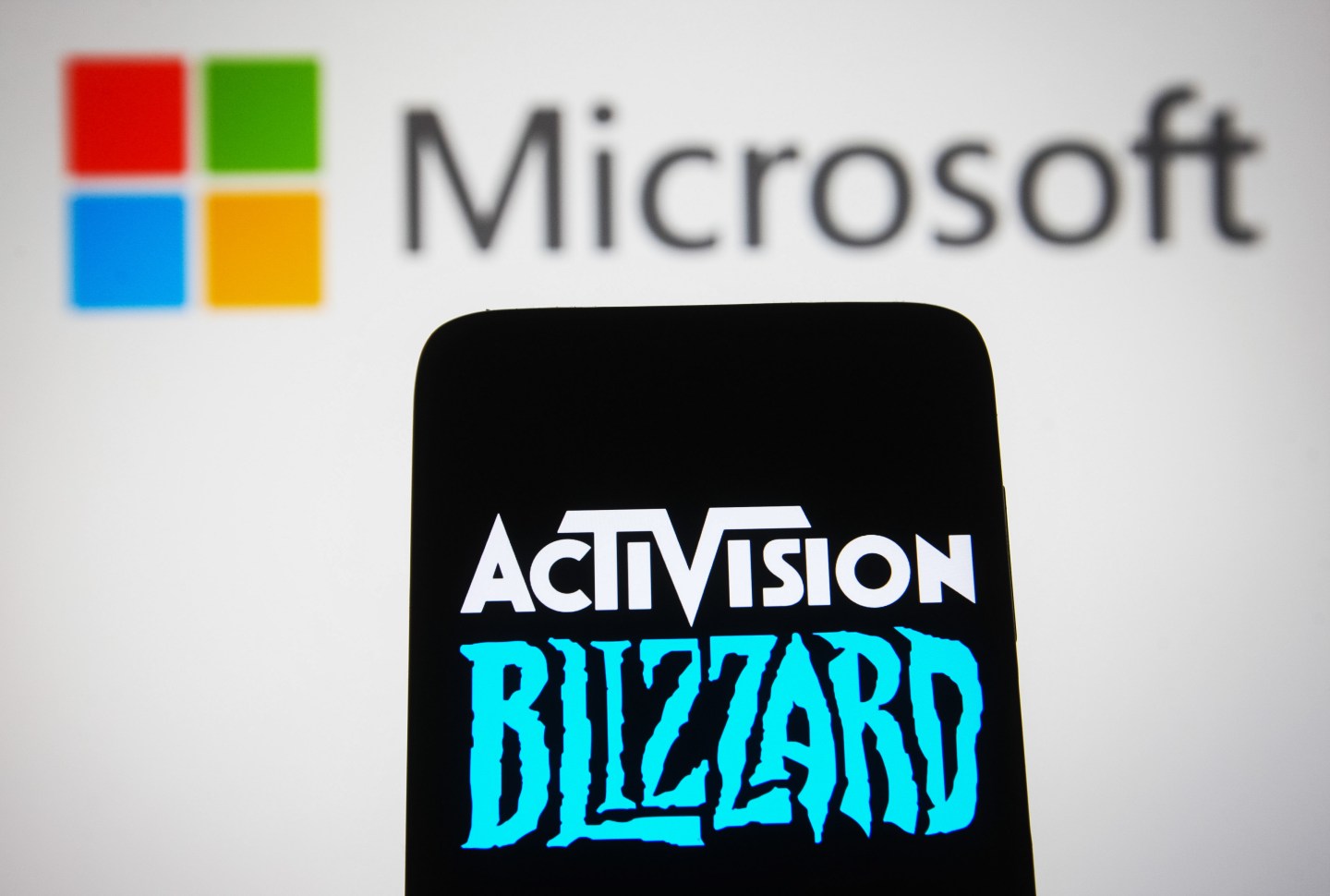 An Activision Blizzard logo in front of a Microsoft logo.