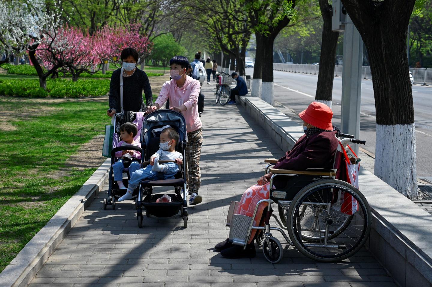 A Chinese family pushes a baby stroller past an elderly woman