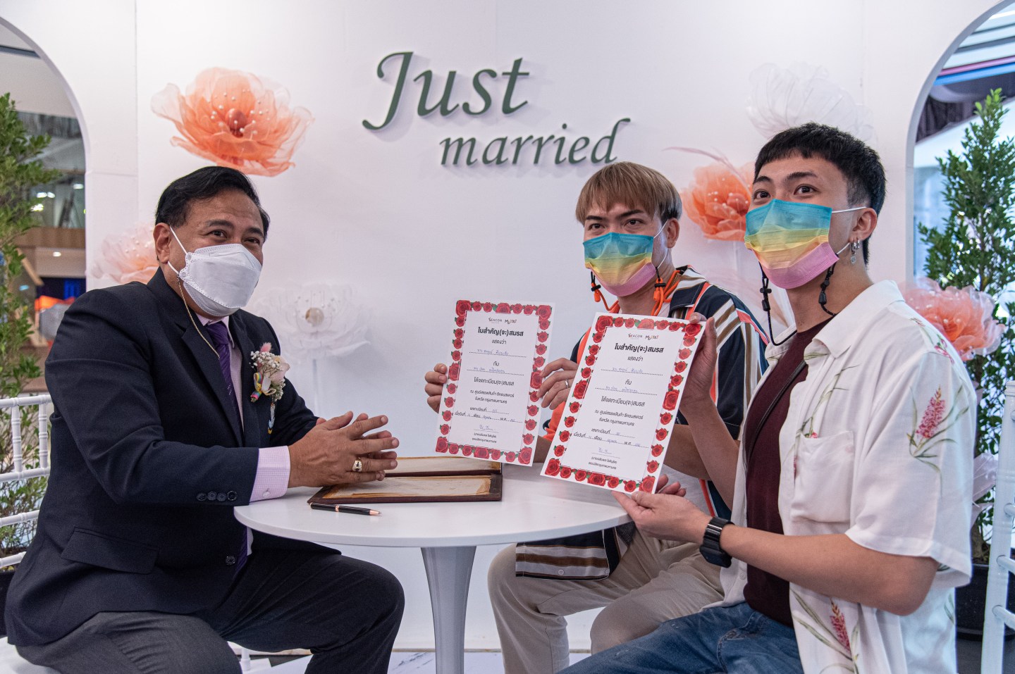 A gay couple holds their marriage certificates