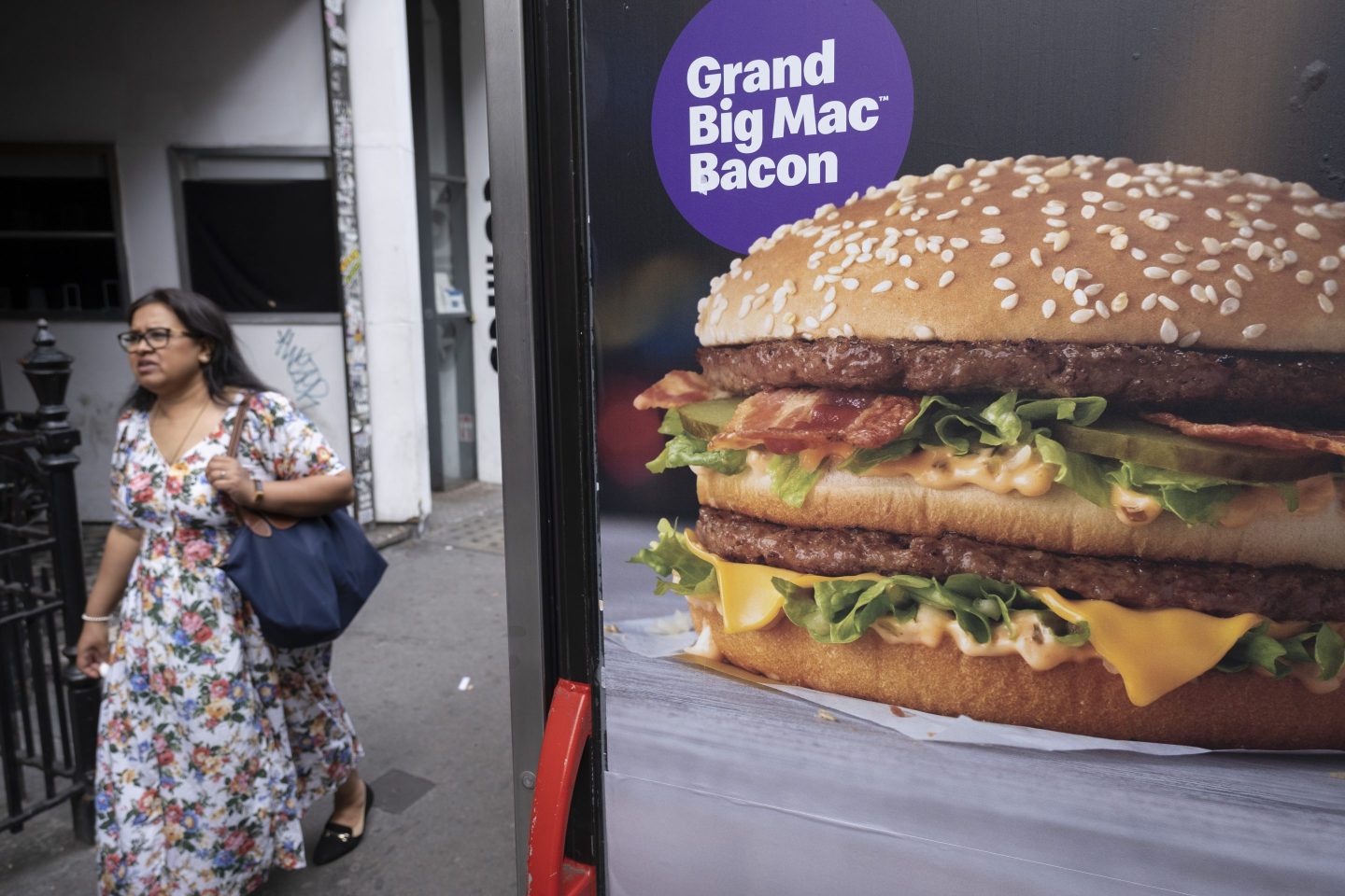 a woman walks past an advertisement for a Big Mac.