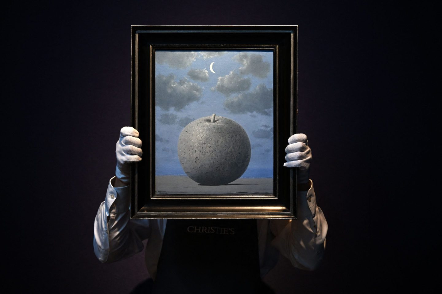 A gallery assistant holds an artwork entitled "Souvenir de voyage" (Remembrance of a Voyage) by Belgian artist Rene Magritte during a photocall at Christie's auction house in London on June 22, 2022.