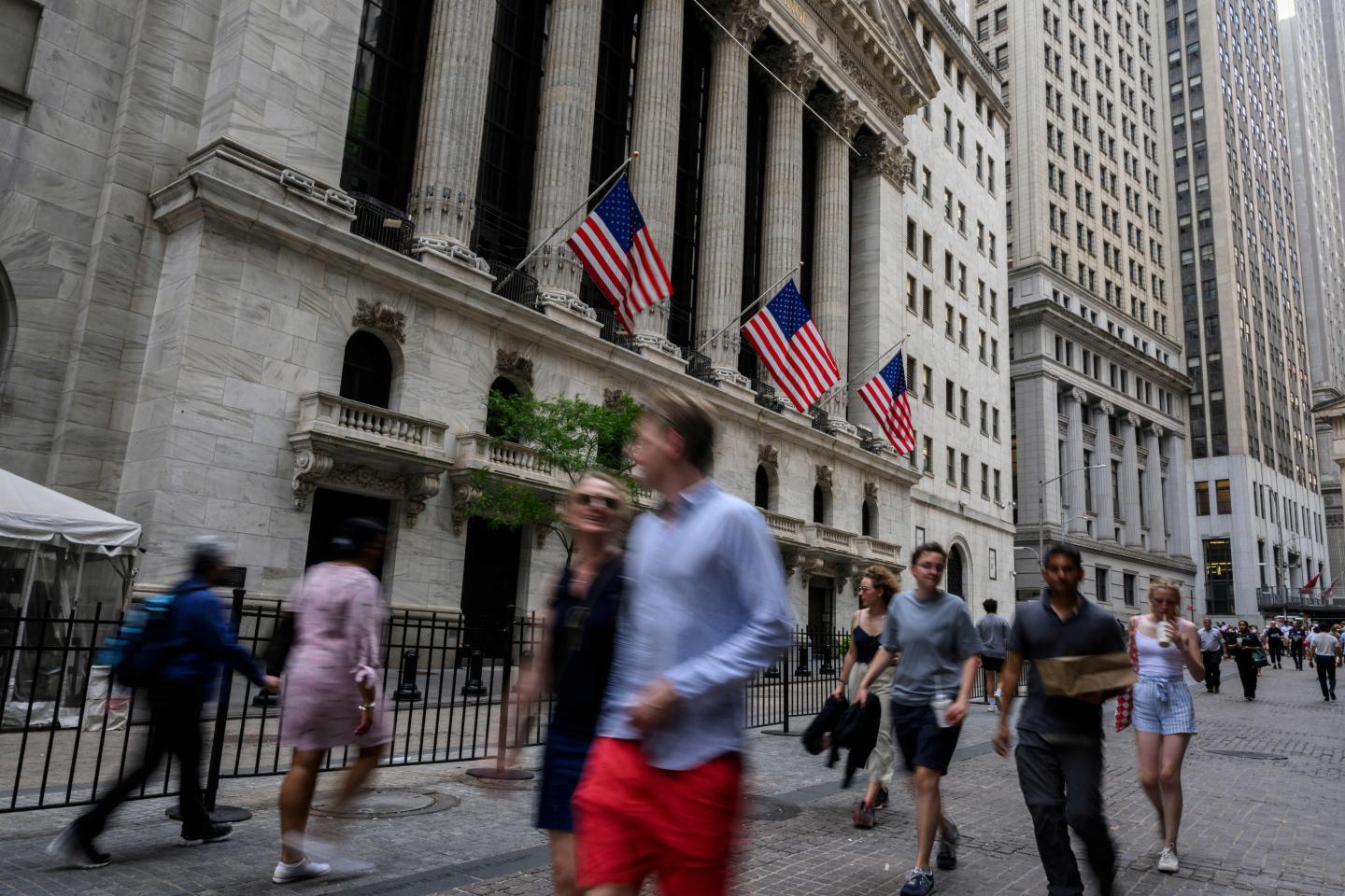 People walk past the New York Stock Exchange (NYSE) on Wall Street.