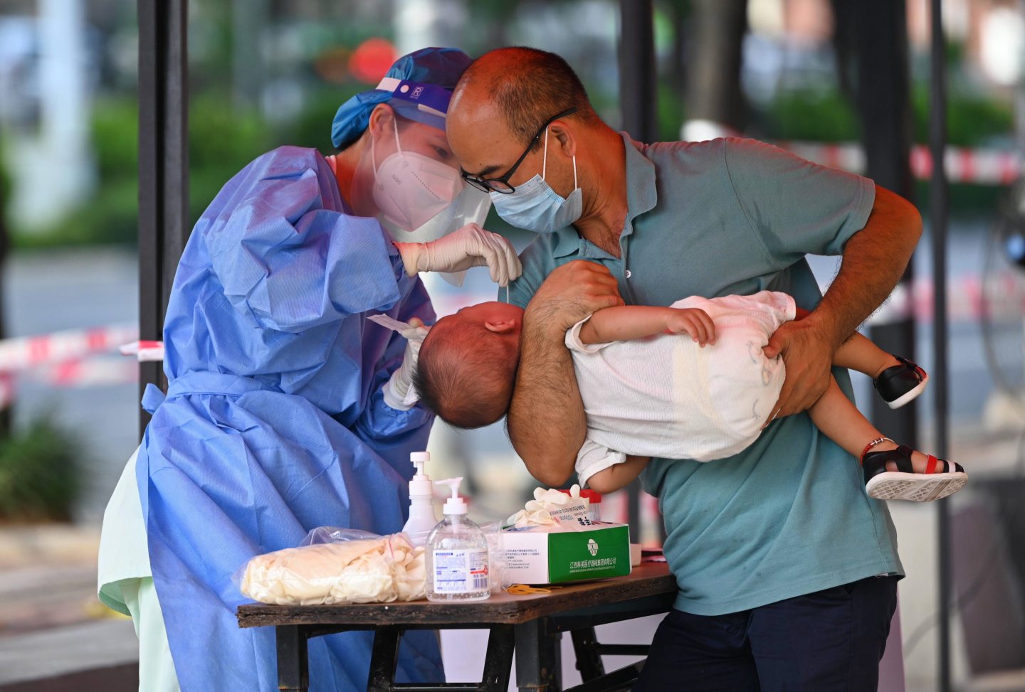 A baby, held by his father, gets a COVID test in China