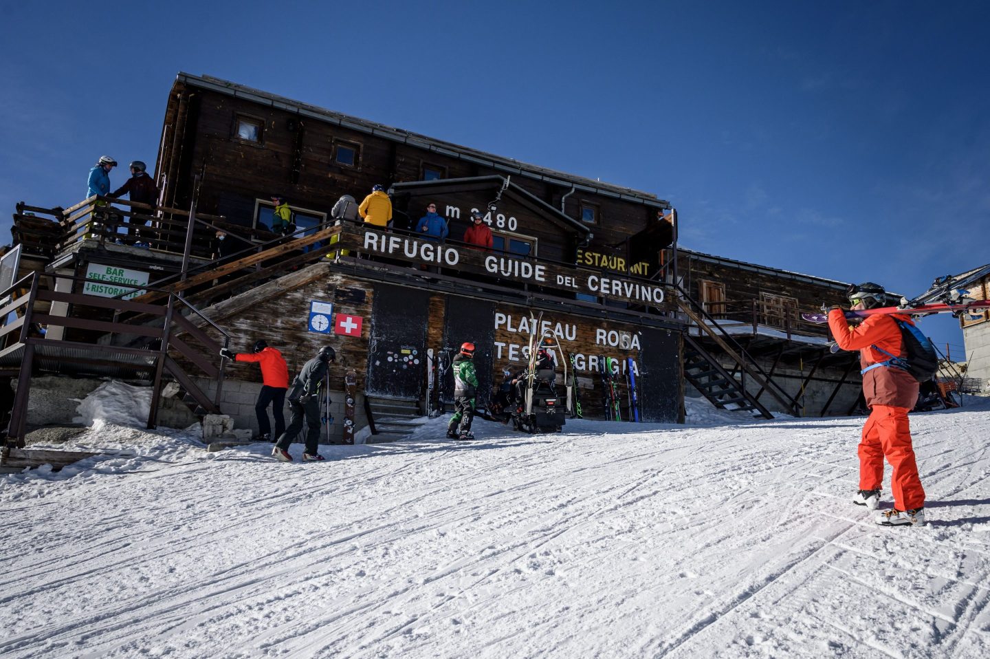 Skiers in front of mountain lodge Guide del Cervino in the Italian Alps